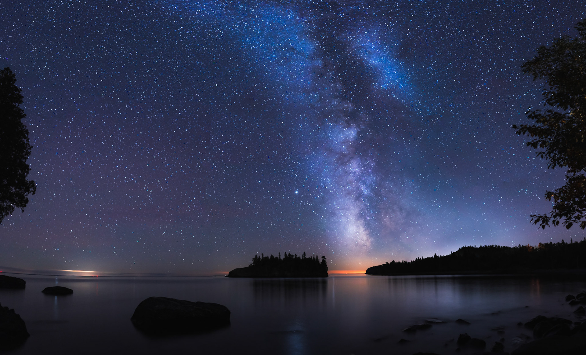 September 17 - September Skies - The Milky Way shines over the North Shore of Lake Superior with the lights of Two Harbors in the background.The Milky Way Galaxy is an incredible work of creation and home to our earth. It is 150,000 light-years in diameter. Our Solar System resides roughly 27,000 light-years away from the galactic center, on the inner edge of one of the spiral-shaped concentrations of gas and dust particles called the Orion Arm.When I look up into the nighttime September skies, the work of God's creation is apparent and humbling. God's Glory: The heavens declare the glory of God; the skies proclaim the work of his hands. Day after day, they pour forth speech; night after night, they reveal knowledge. They have no speech; they use no words; no sound is heard from them. Yet their voice goes out into all the earth, their words to the ends of the world. (Ps. 19:1-4)