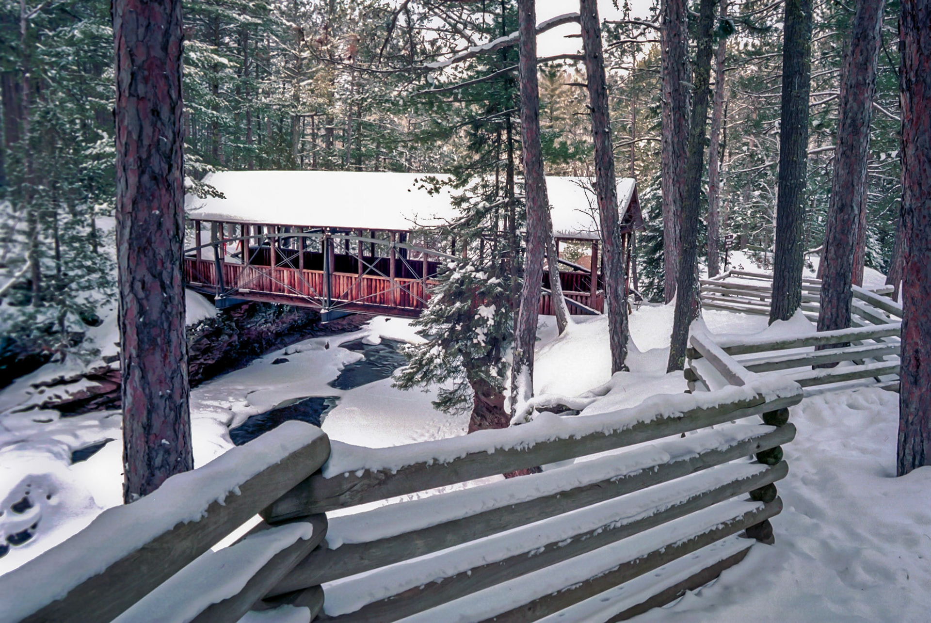 January 13 - Bowstring BridgeThe Bowstring Bridge, also called the Horton Bridge, spans the Amnicon River and graces Amnicon State Park's landscapes near Superior, Wisconsin.Located in the Poplar River valley, when snow falls, it intensifies in this sheltered pine landscape, magnifying the beauty of a recent storm.The sound of running water, chirping chickadees, and a gentle wind blowing through the treetops gives you a sense of peace that only being in nature can provide.Let the field exult, and all that is in it.Then all the trees of the forest will sing for joy. Psalm 96:12You may have a hectic day ahead; use this image of God's handiwork to find peace in the deep woods.