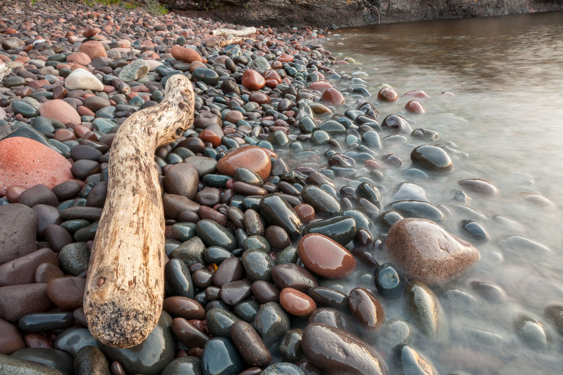 September 19  - Shoreline BouldersAs the sun rises over Lake Superior's tranquil waters, the rounded boulders look like eggs pushed up from the bottom of the lake. Here, a large driftwood log lays along the shoreline of Split Rock State Park located on the North Shore of Lake Superior.With dawn breaking on the calm waters of the big lake, a refreshing mist cools your face and refreshes your soul, knowing that your God mixed these elements for our enjoyment and His Glory.The Power of God The Lord is my rock and my fortress and my deliverer, my God, my rock, in whom I take refuge, my shield, and the horn of my salvation, my stronghold. Psalm 18:2