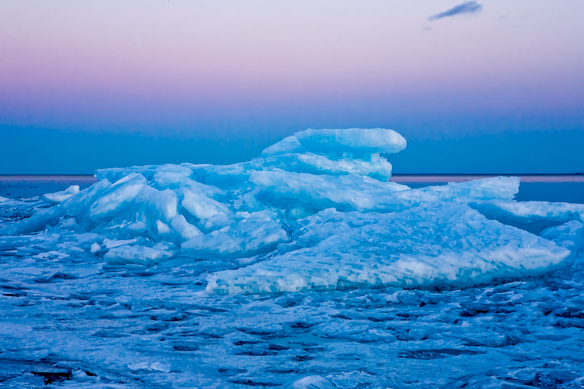 March 7 — Evening IceIn this scene, ice chunks piled high reflect and refract the magenta evening sky into a stunning sight to remember. March is a wonderful month to watch nature awaken. Daylight hours are rapidly expanding, wildlife is stirring, and plants are beginning to wake up, still deep under the snow. A springtime walk along Lake Superior's shoreline makes it impossible to miss the changing season. The colors, climate, and fresh air unite to announce that a new season has begun.While temperatures often fail to reflect the arrival of spring, look closely at the melting snow, opening waterfalls, and birds beginning to nest — life is returning to the Northland. Like waking up early without coffee, it takes time to fully wake up, yet the energy of renewal is already beginning to "Flow With the Seasons"."Calling the light' day,' and the darkness' night.'The twilight and the dawn were day one." — Genesis 1:5The ice will soon melt away, but the memory of how God shaped these elements will remain. Remember, God placed this day together and set you within it — to enjoy it and to give Him glory.