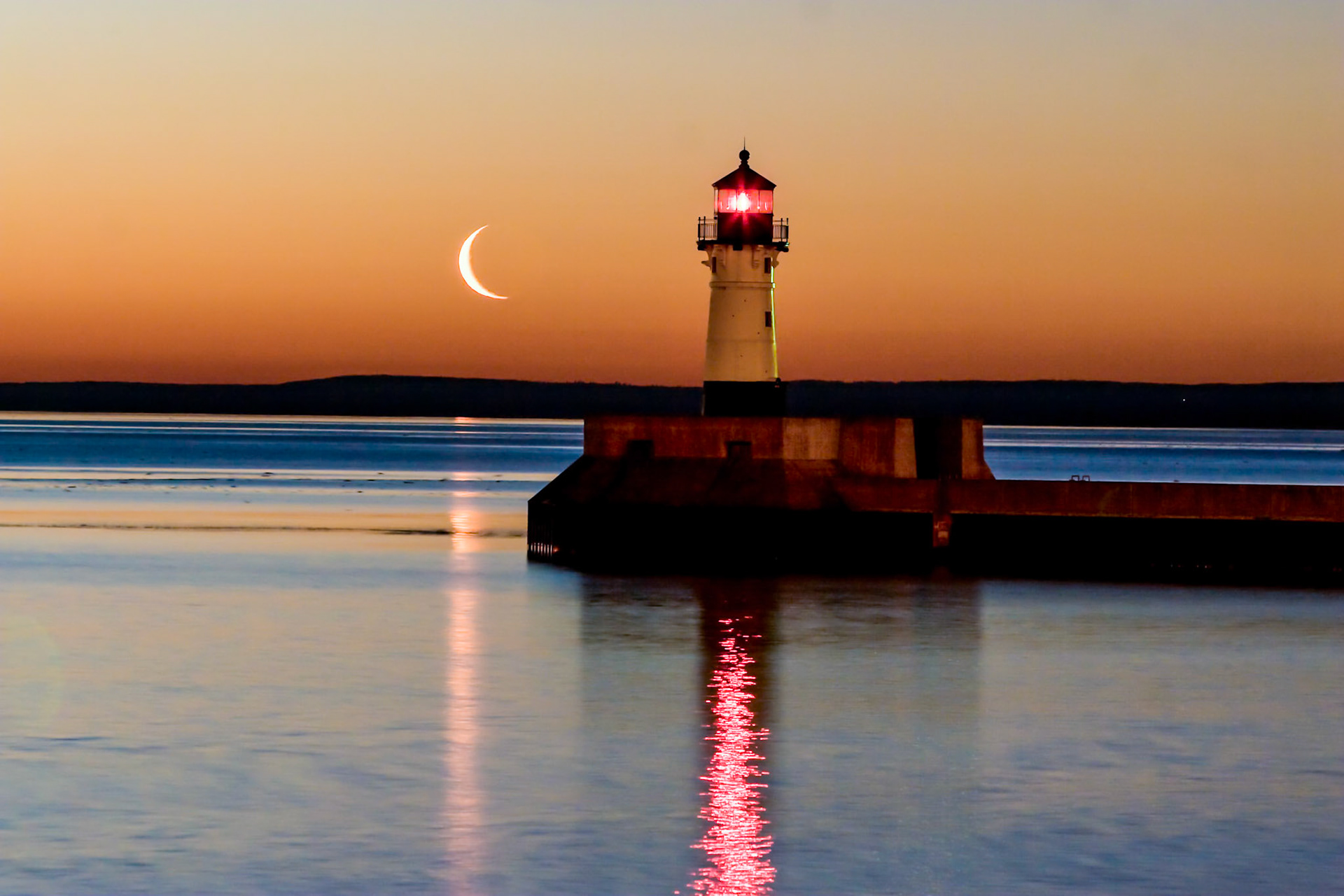 March 26 — Crescent MoonThe early morning moonrise over Canal Park in late March is a beautiful sight to photograph. Quiet waters and saturated colors offer a refreshing start to the day.At this time of year, Earth’s tilt creates longer dawn transitions in northern latitudes. A fading crescent moon often lingers near sunrise, allowing night and day to overlap in a gentle exchange of light briefly.There is something peaceful about the lighthouse and the moon in this scene. They quietly set the stage for the approaching day. The moon is fading, the sun has not yet fully arrived, yet calmness remains. Like the flow of the seasons, change begins subtly. Winter does not disappear overnight, but the light increases daily.In life, we often stand in that same in-between space — not fully in darkness, not fully in daylight. Still, the Light of Christ remains.“He made the moon to mark the seasons; the sun knows its time for setting.” — Psalm 104:19We are already 83 days into the year. Take a deep breath, make the most of today, and enjoy the day God has given you. There will never be another like it.