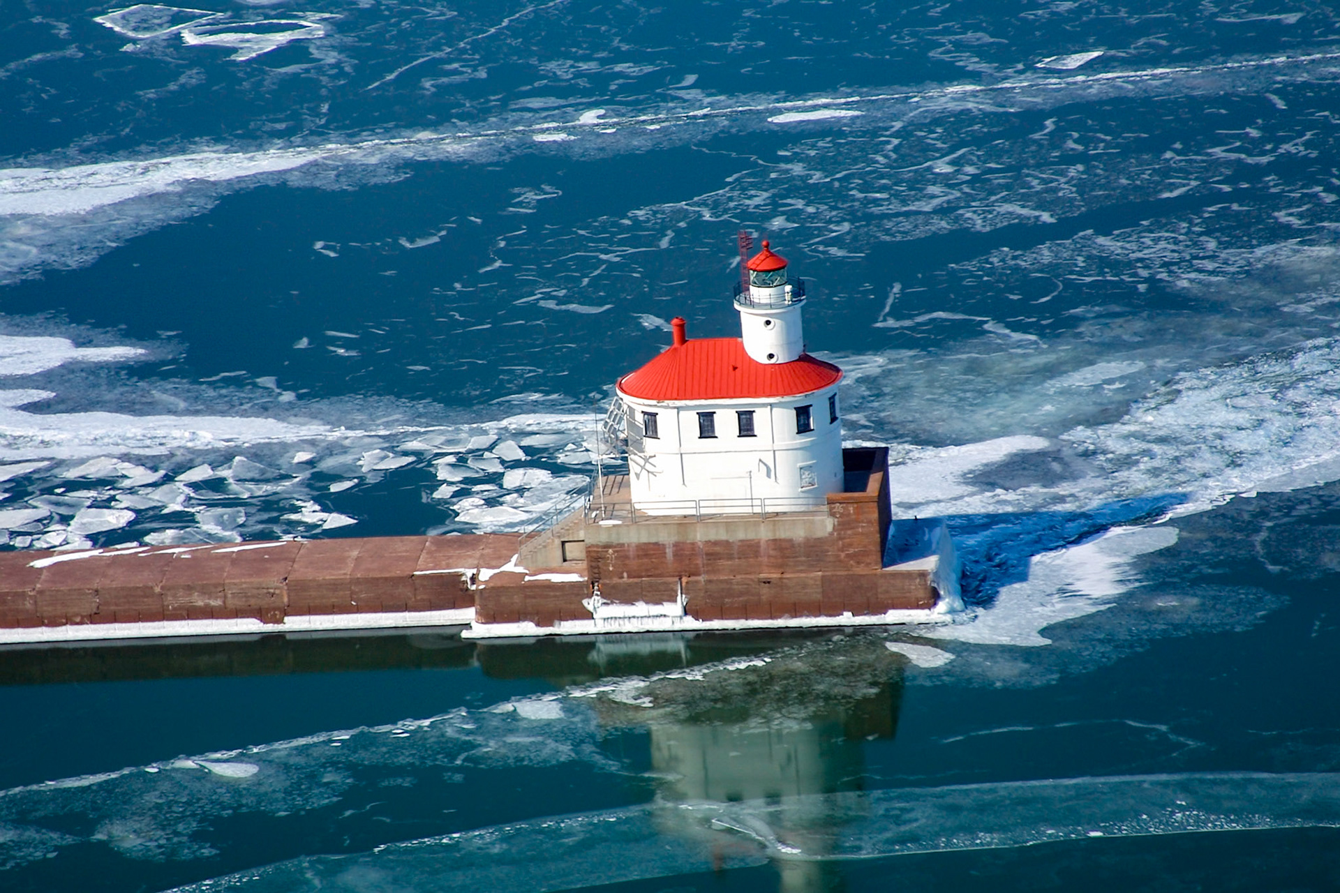 January 5th - Icy Reflections - Wisconsin Point LighthouseThe Wisconsin Point Lighthouse reflects beautifully in the transparent ice surrounding the entrance to the Duluth-Superior Harbor.Built in 1913, the Wisconsin Point Lighthouse has watched over the Wisconsin Entry for over a century. This stunning lighthouse has withstood high winds, powerful waves, lightning, and extreme cold throughout the years. It stands as a testament to the construction crews and engineers who designed and built it.Wisconsin Point Light is one of my favorite lighthouses in the area, and it's definitely worth taking a scenic drive down Wisconsin Point to see it for yourself."The LORD is my rock, my fortress, my deliverer, my God, my rock, in whom I take refuge, my shield, and the horn of my salvation, my stronghold." - Psalm 18:2Often overlooked, the Wisconsin Point Lighthouse is not only a marvel of architecture but also an emblem of resilience.