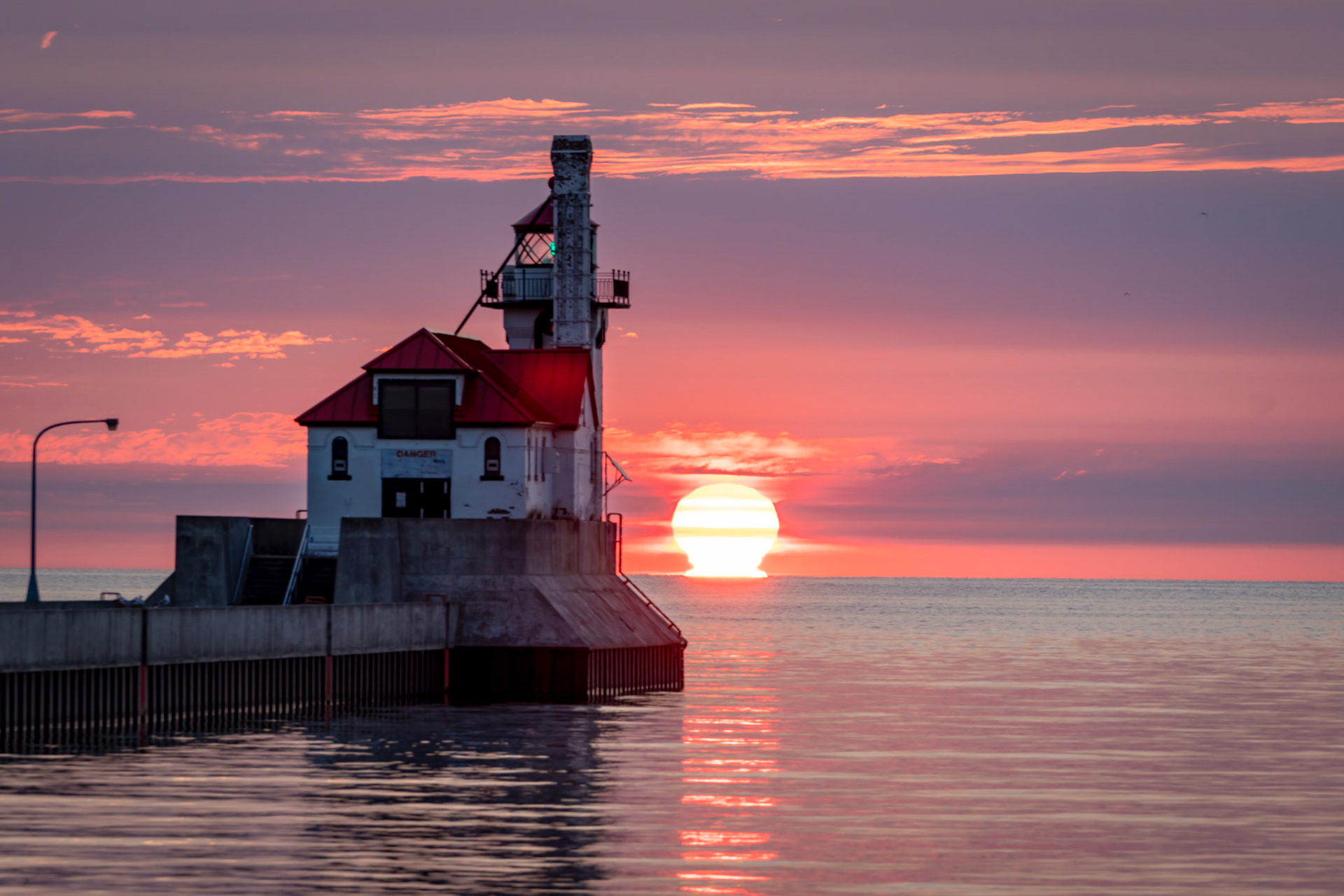 July 28 - Pastel Morning - On July 28, I enjoyed a serene morning at the Duluth South Pier Lighthouse, where I witnessed a beautiful late July sunrise over the horizon. It was fascinating to observe how the shape of the sun appeared distorted near the horizon due to the refraction of light near the water surface of Lake Superior.The sound of the gulls, the waves gently lapping the beach, and the cool, fresh air from the lake created beautiful memories."And God said, 'Let there be light,' and there was light." - Genesis 1:3