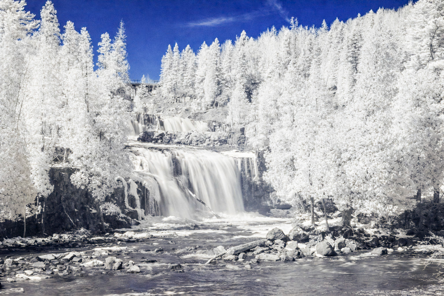 March 6 - Invisible LightThis image of Gooseberry Falls was captured with a specialized camera that detects more than our eyes do. Human vision is limited to visible light, but digital sensors can detect a wider spectrum. To create natural-looking photos, manufacturers block infrared light with an internal filter. In this image, the filter was removed, allowing the camera to record near-infrared light.Plants reflect large amounts of infrared light to prevent overheating. That’s why trees glow white, grass appears snowy, and leaves shine so brightly. It’s a hidden layer of beauty — always present, yet invisible to our natural sight.It’s amazing how something so real can surround us every day and still go unseen.“For since the creation of the world God’s invisible qualities—his eternal power and divine nature—have been clearly seen, being understood from what has been made…” — Romans 1:20Like infrared light, God’s presence is not always visible to our eyes, yet His fingerprints are everywhere. When we view creation through the lens of Scripture, we begin to see what has been there all along — quiet evidence of a loving Creator working behind the scenes.