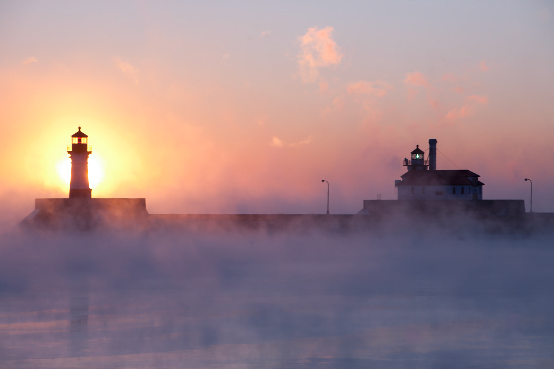 Sea smoke envelopes the sunrise and lighthouses in Canal Park. The intense cold of a passing "Polar Vortex" generated sea smoke to envelope the mid-January dawn.This is the day that the Lord has made; let us rejoice and be glad in it. Psalm 118:24While Mid-January is deep winter, the fact is that daylight hours are getting longer, the average temperatures are now rising, and the cold snaps will soon be shorter.Nature declares that hope is rising for better days ahead, just as God promises hope in Him by using His creation to prove it.