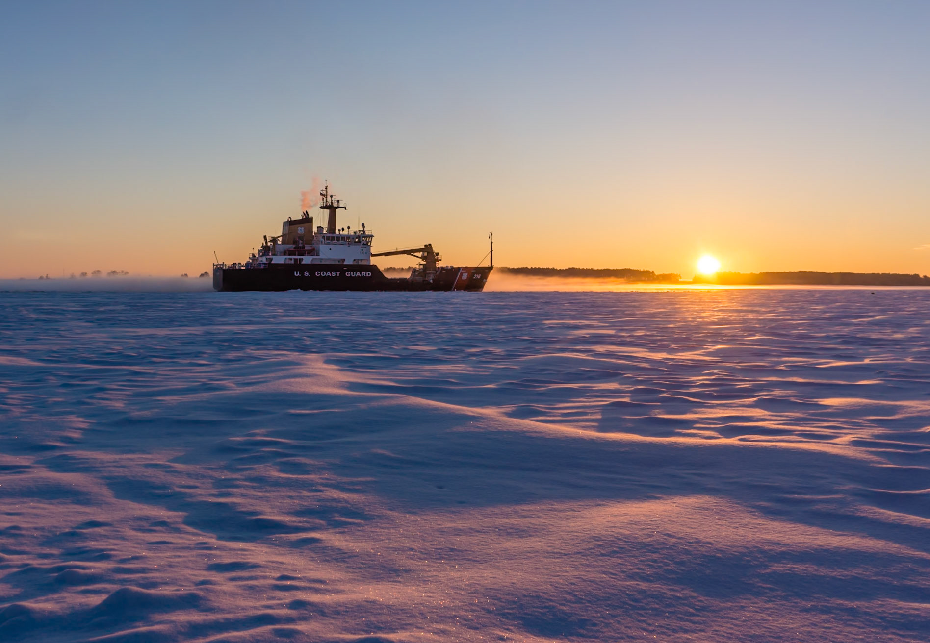 March 11 - Ice BreakingA Coast Guard cutter breaking ice in the Duluth Harbor, preparing for the shipping season, is a sure sign of spring. With vast stretches of thick ice to break up before the season opens in a week, the Coast Guard works alongside the warming days and increasingly powerful sun to usher in the new season.With an increase of nearly three hours of daylight since the first of the year, spring is pressing its way in—slow but sure—much like the icebreaker at work.While the ice field in the image looks firm and solid today, it will likely fracture and drift out into Lake Superior within days, forcing ice fishermen to retreat to their boats.“Look at the ships also, though they are so great and are driven by strong winds, are still directed by a very small rudder wherever the inclination of the pilot desires.” — James 3:4Like the ice field, our foundation may appear firm today—but what about tomorrow? Are small cracks beginning to form? Christ is our assurance, steady and true, for both today and tomorrow.