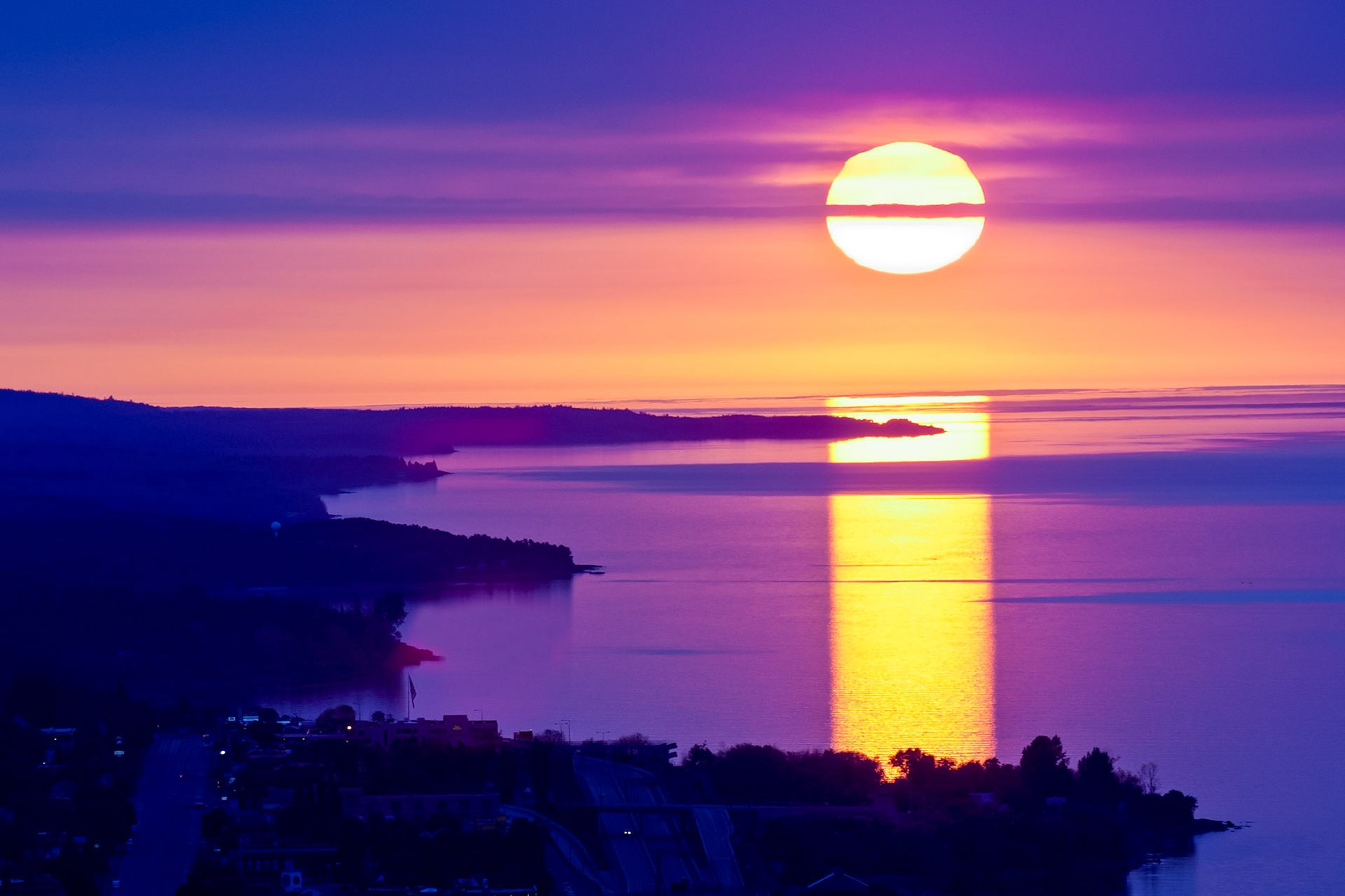 July 5 - Distant Horizon - In mid-summer, the azimuth of the sunrise is once again moving south, and soon we will notice the shorter daylight hours. Looking up the North Shore of Lake Superior on a summer morning is a refreshing sight and a reminder that time is moving on.Light passing through the dense, moist surface air leaves the stronger magenta wavelengths to shine through.For thou wilt light my candle: the Lord, my God, will enlighten my darkness. Psalm 18:28