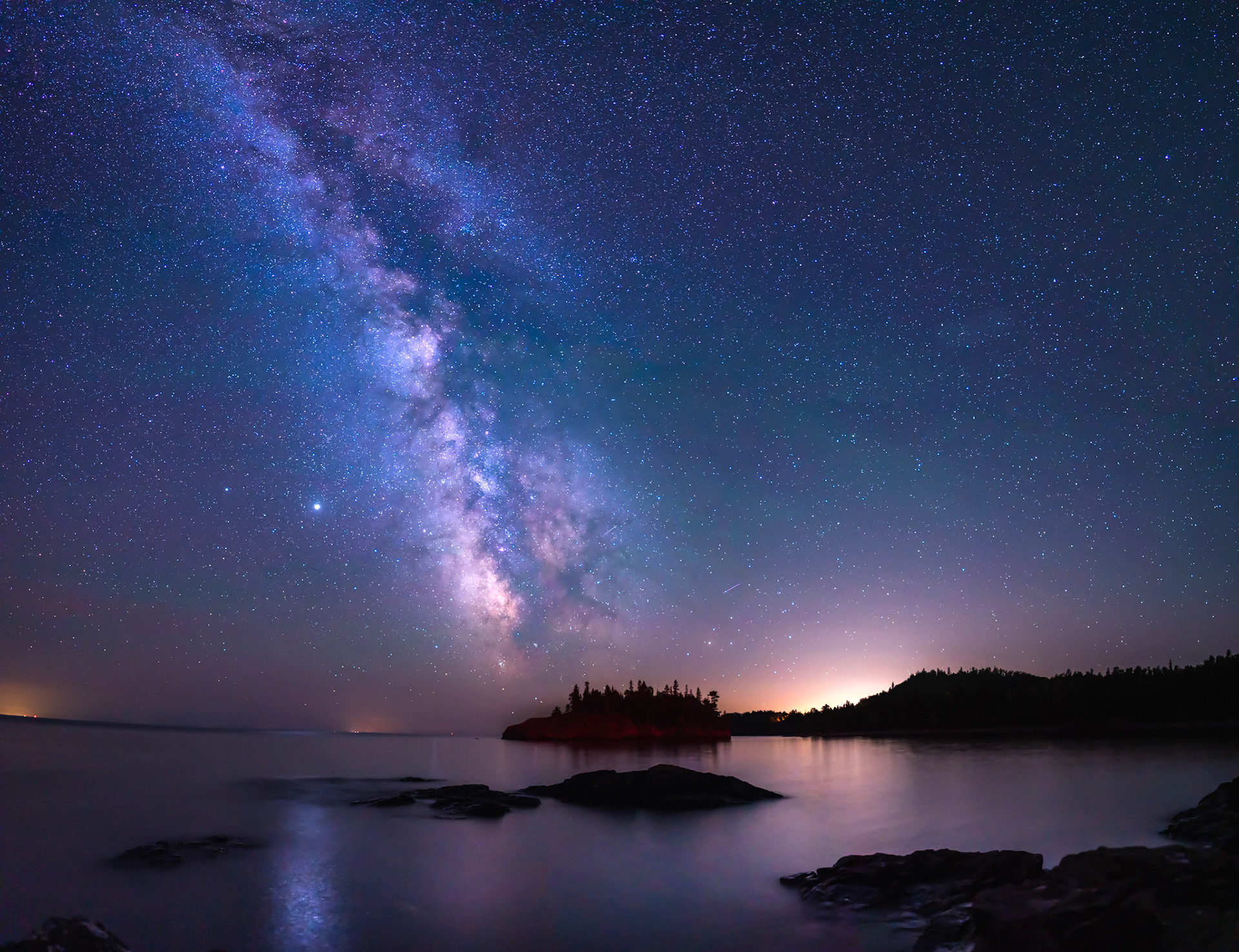 August 16-Distant Fire August's Scattered thunderstorms highlight the horizon as the Milky Way drifts across the August sky at Split Rock State Park.The quiet beauty of the universe reflecting off Lake Superior is a humbling reminder of God's creation.Lift your eyes and look to the heavens: Who created all these? He who brings out the starry host one by one and calls forth each of them by name. Because of his great power and mighty strength, not one of them is missing. Isaiah 40:26