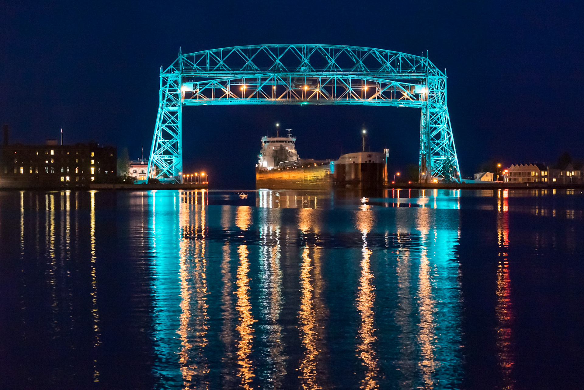 With the Duluth Aerial Lift Bridge lit in teal color to bring attention to ovarian cancer, a laker arrives for another load of taconite.