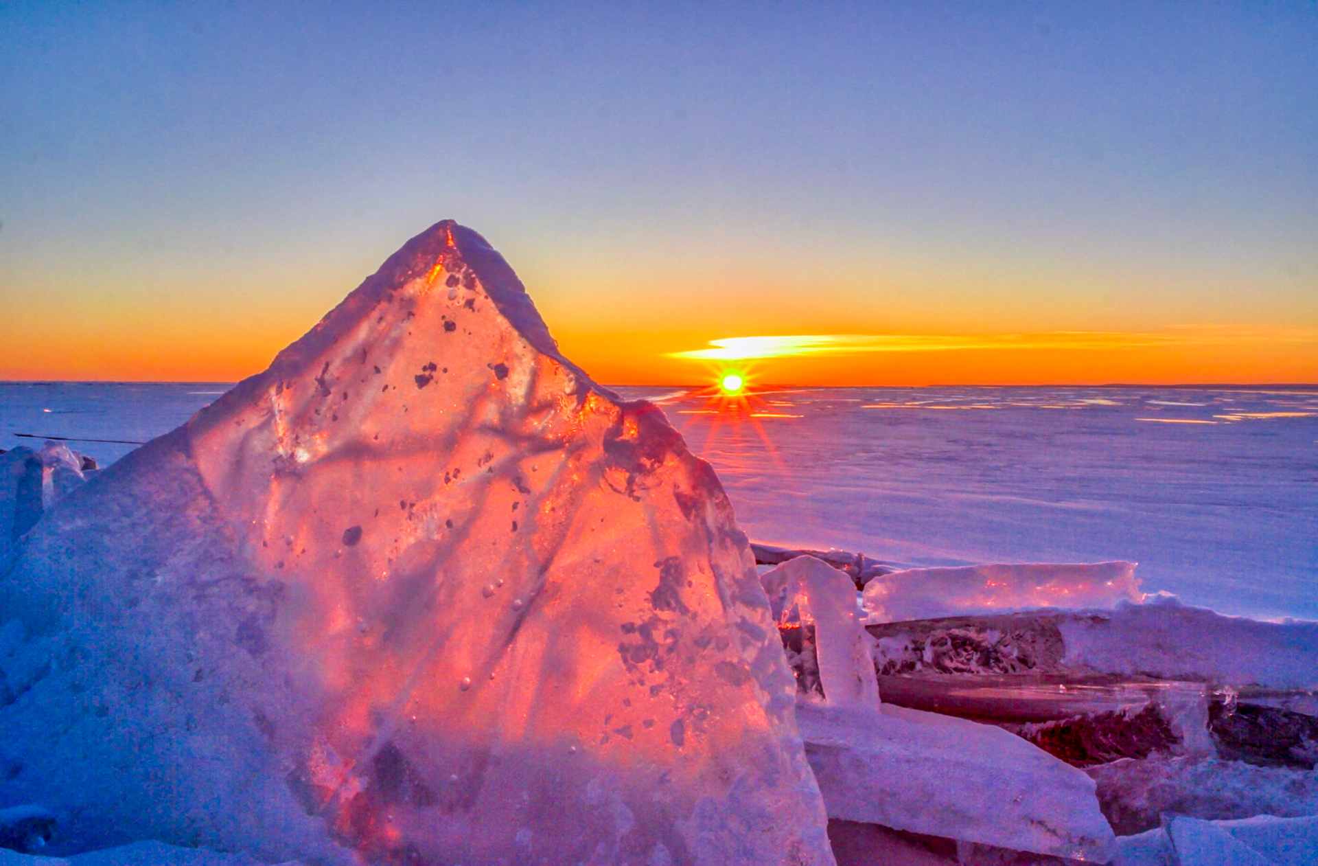 February 17 - Ice Shards on the North ShoreLate winter ice shards are the attraction of the north shore of Lake Superior during late February. The ice forms a crystal necklace along the shorelines for a short time when the seasons transition from winter to spring.The beams radiating from the sun are an optical diffraction effect created by the blades of the camera aperture. The edges of the aperture blades bend the light waves, creating the rays. That's why landscape photographers love sunrises and sunsets for dramatic starbursts.A simple scene like this tends to wash away the cares and concerns of the day. It helps put things into perspective and resets our thoughts.But if we hope for what we do not see, we wait for it with patience. Romans 8:25Hope is a driving force in life, and if we look around us, we find just enough for today. Faith is the same; you can't store it, but you can apply it to today.