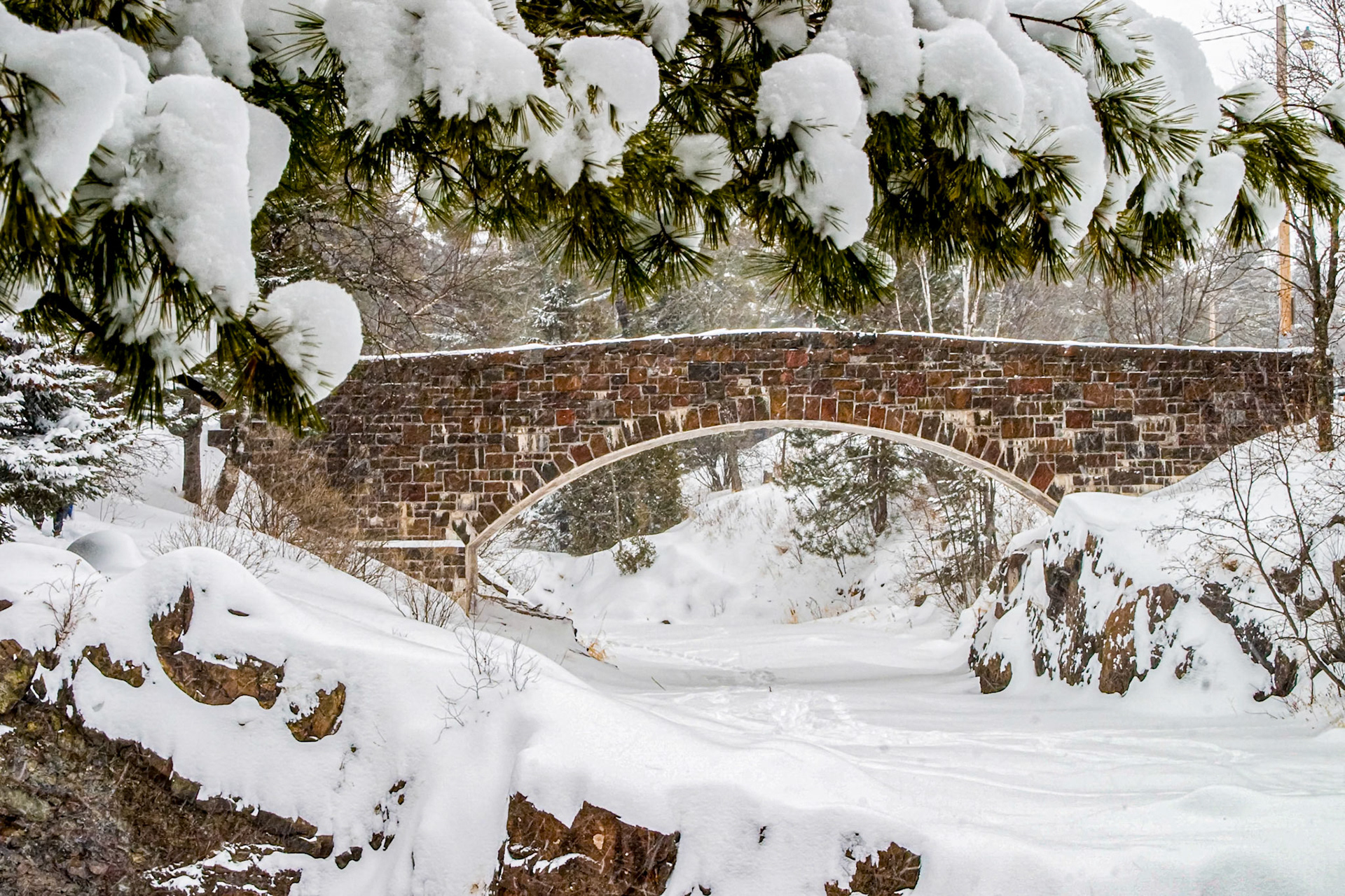 January 26 - Snow BridgeA blanket of freshly fallen snow covers the landscape around the Lester River Bridge in Duluth. The joy of winter is the quiet peacefulness surrounding you on a walk up a frozen river. The occasional chirp of a chickadee or squawk of a raven breaks the silence, only to return to peaceful quiet.You keep him in perfect peace, whose mind stays on you because he trusts you. Isaiah 26:3The only peace and safety in this world is hope and faith in our Lord and Savior, Jesus Christ.