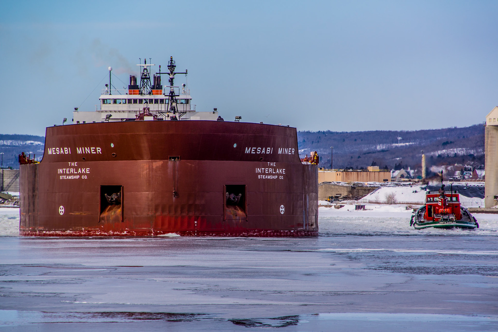 March 21 – Springtime WakeupThe 1,000-foot Mesabi Miner gets help from tugs as she breaks free from months of winter layup. After weeks of stillness, she moves again—steel against ice, power against resistance—carving a path through Duluth Harbor.When a fully loaded freighter like the Mesabi Miner passes beneath the Aerial Lift Bridge, more than 21 million gallons of water are displaced—nearly 400,000 bathtubs. The harbor doesn’t ignore her presence. It responds. Water rises and falls—ice shifts. Everything adjusts to movement.The return of the big ships is a sure sign that spring has arrived along Lake Superior. Throughout the layup, there has been maintenance, renewal, and preparation. Now the vessels are ready for a fresh start. The shipping season begins again, reminding us that seasons of waiting are not wasted—they prepare us for what comes next.The seasons MARCH on, and so do our days. Time does not pause, even when we do.“So teach us to number our days that we may gain a heart of wisdom.” — Psalm 90:12Enjoy today. It is a fresh start, and there will never be another quite like it.