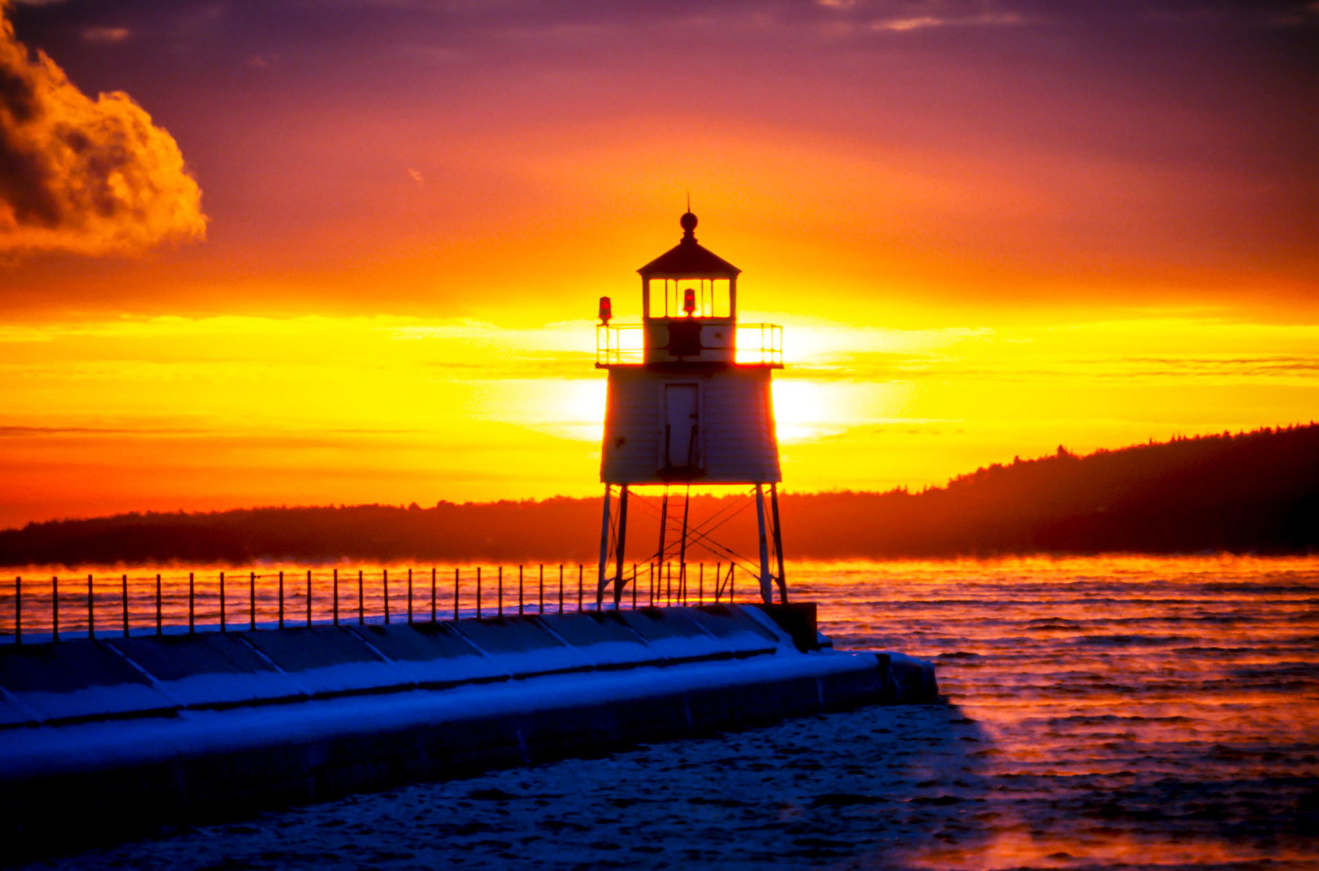 January 21 — Winter SunsetTwo Harbors Breakwater LighthouseBuilt in 1892, the Two Harbors breakwater lighthouse has stood watch for more than a century. Together with the nearby historic lighthouse, it has guided mighty U.S. Steel ships safely into harbor through fog, darkness, and winter storms.The structure rises 49 feet above the breakwater, while its beacon shines 78 feet above the waters of Lake Superior—a steady point of reference in an often-unforgiving place.On a cold January evening, the setting sun pours warm color across the scene. Though the air is bitter, the light softens everything it touches, reminding us how color and contrast can transform even the coldest moments into something that feels welcoming.For with you is the fountain of life; in your light do we see light. Psalm 36:9Today is a great day to be alive—a fleeting gift, lasting only as long as the sea smoke.