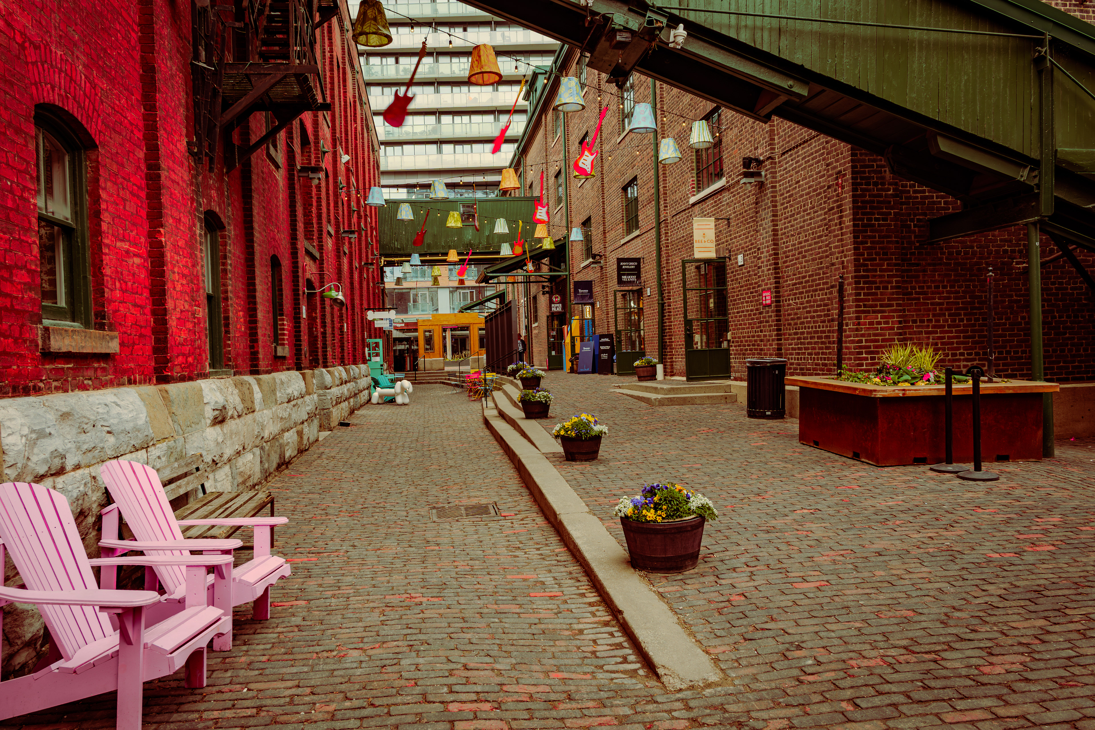Colorful alley in Toronto’s Distillery District lined with vintage brick, patio chairs, and overhead hanging guitars.