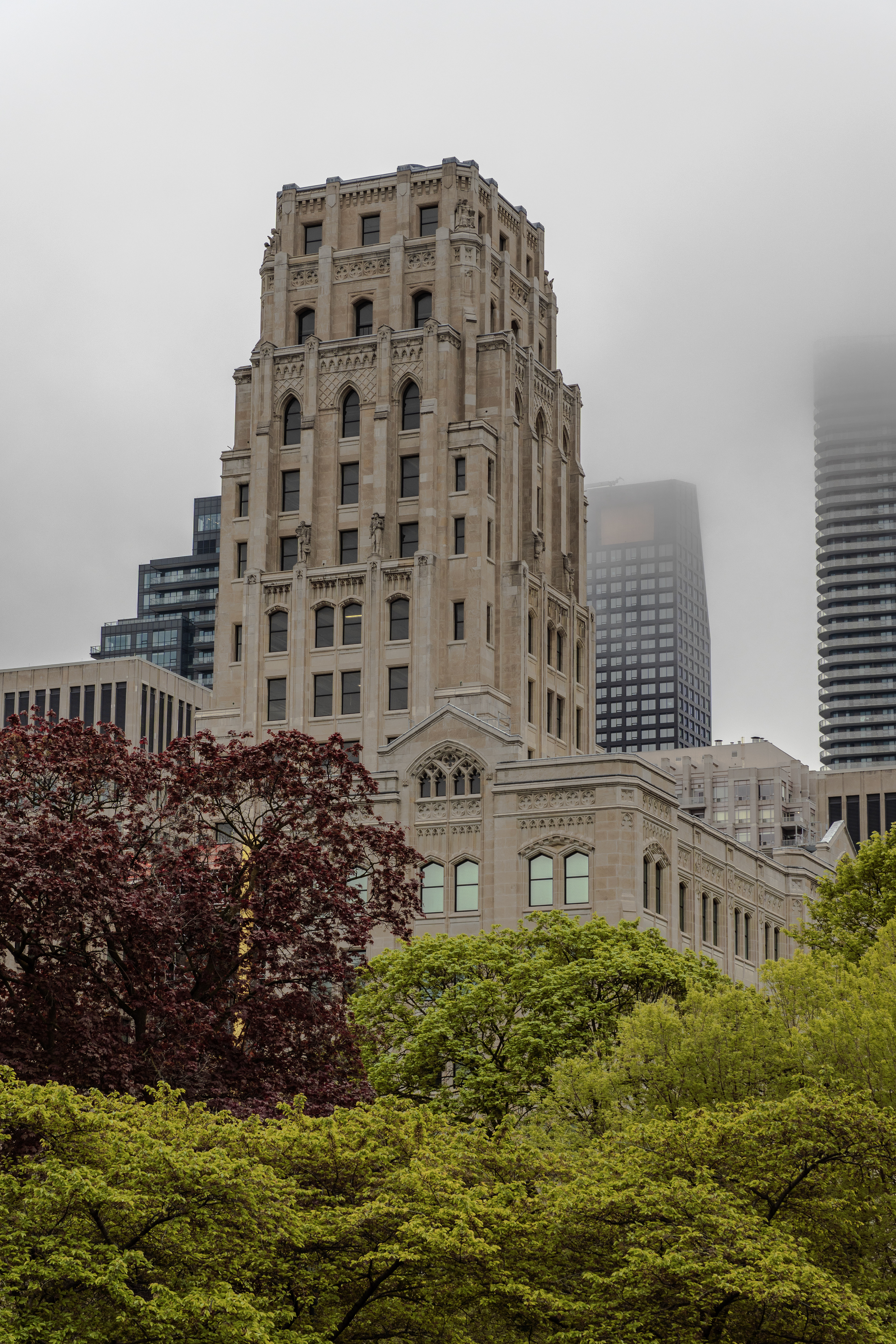 Whitney Block Tower standing tall among the fog and modern high-rises in Toronto