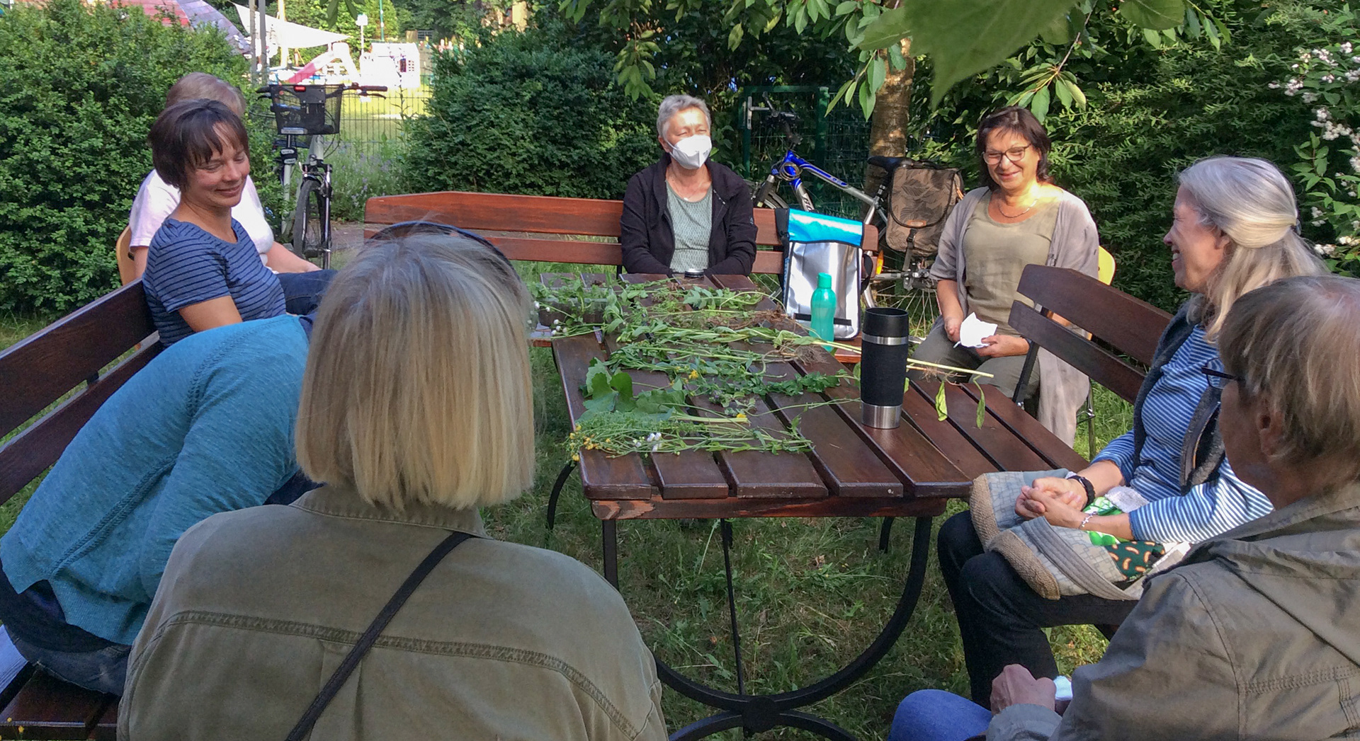 Der Beetklub Lindwedel sitzt gemeinsam um den Tisch im Schulgarten.