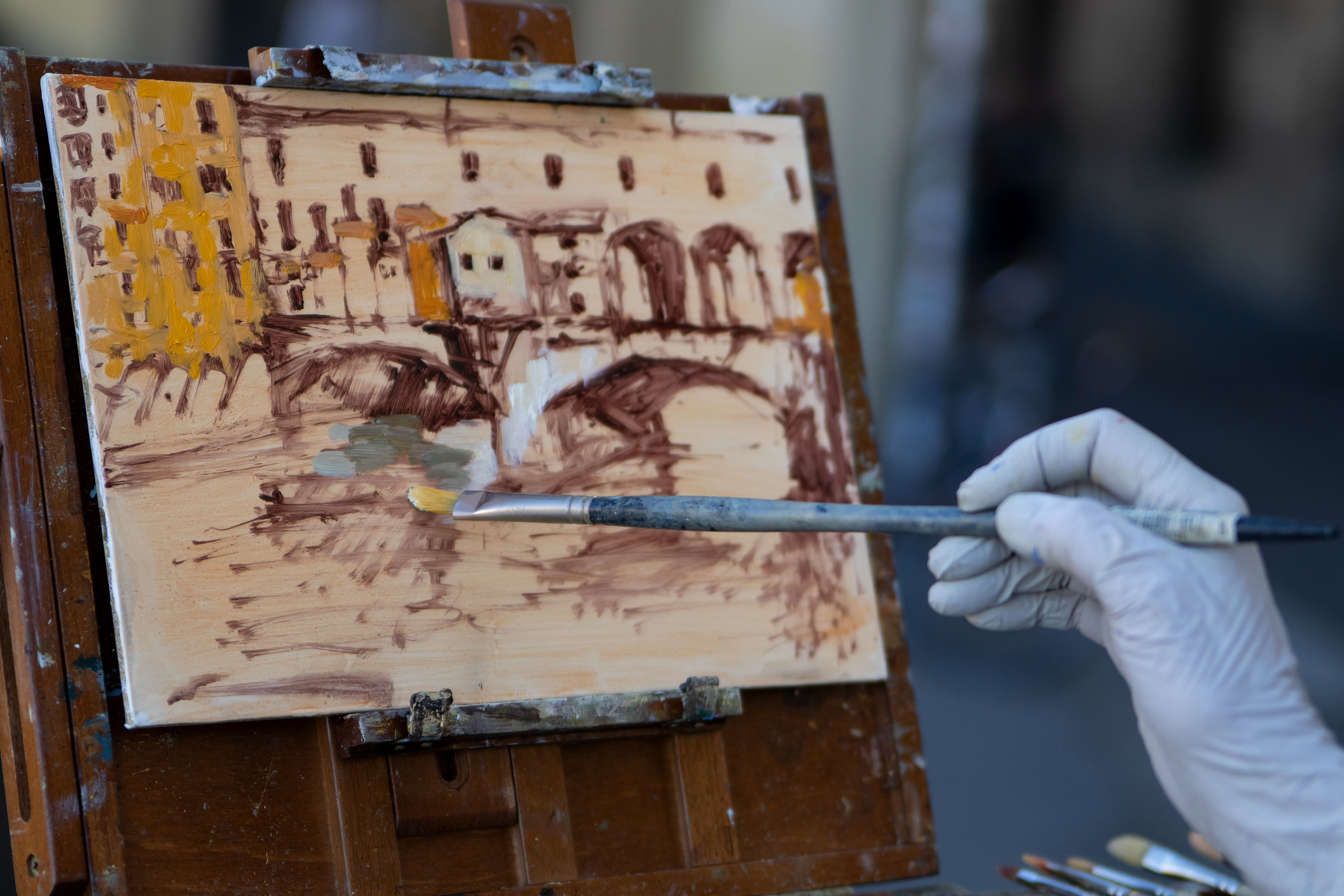 California Hartland college professor, Georgesse Gomez, paints the color on a wooden palette of the “Ponte Vechio” bridge in Florence, Italy on Saturday, May 31, 2025. 