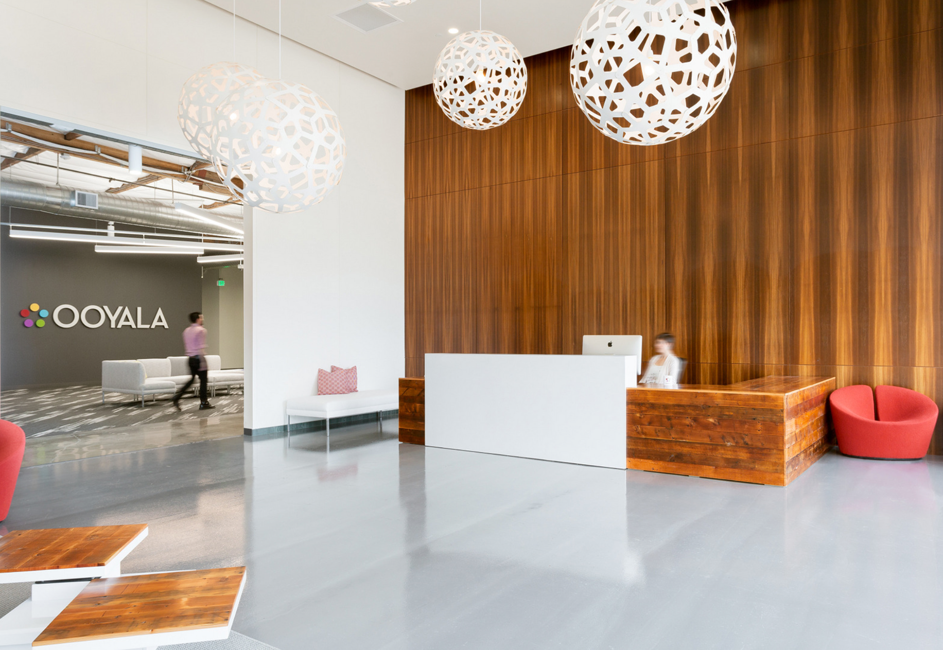 Ooyala Silicon Valley office lobby with the Ooyala logo on the wall, a wood-paneled reception desk and white pendant lights
