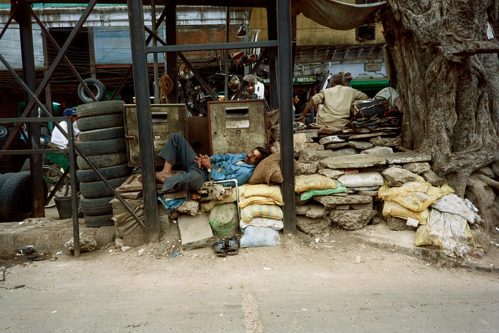 India Downtown New Delhi, it is hot and a man is taking a nap in the middle of the noisy street.