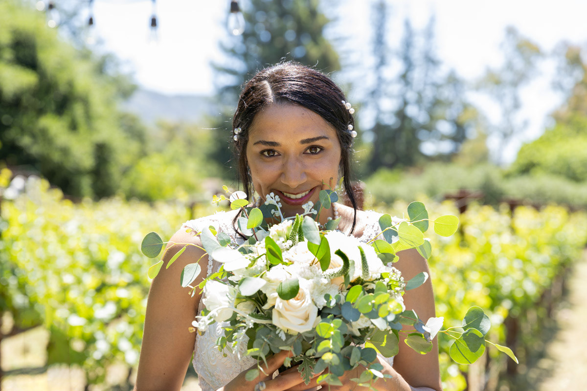 bride-looking-over-top-of-bouquet-with-napa-vineyard-behind
