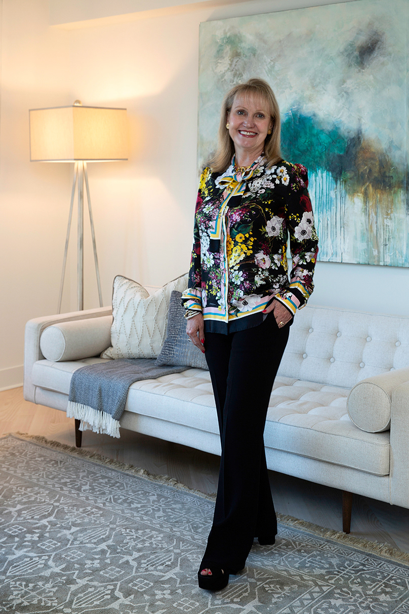 woman-in-slacks-and-floral-blouse-standing-sofa-painting