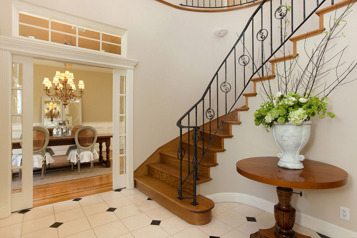 cream-colored-foyer-with-floral-arrangement-on-table--dining-room-entry-and-wrought-iron-staircase