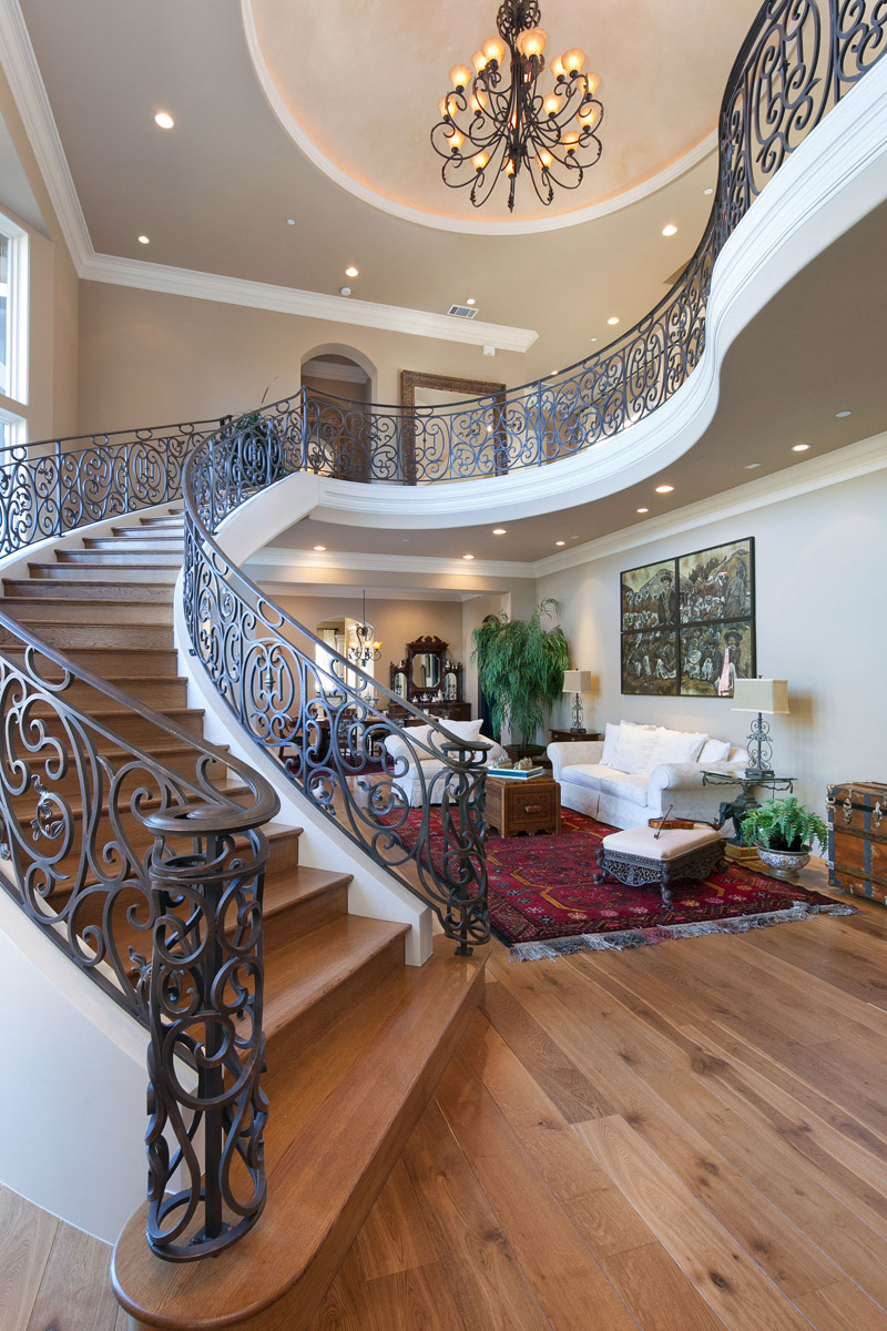 elegant-curving-black-wrought-iron-staircase-with-chandelier-above