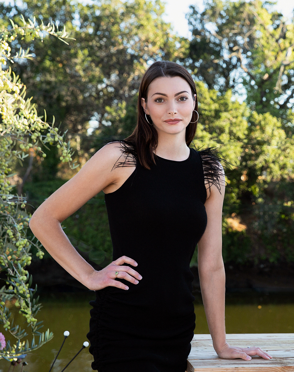 young-woman-in-garden-wears-hoop-earrings-and-Azadeh-Couture-black-feather-dress