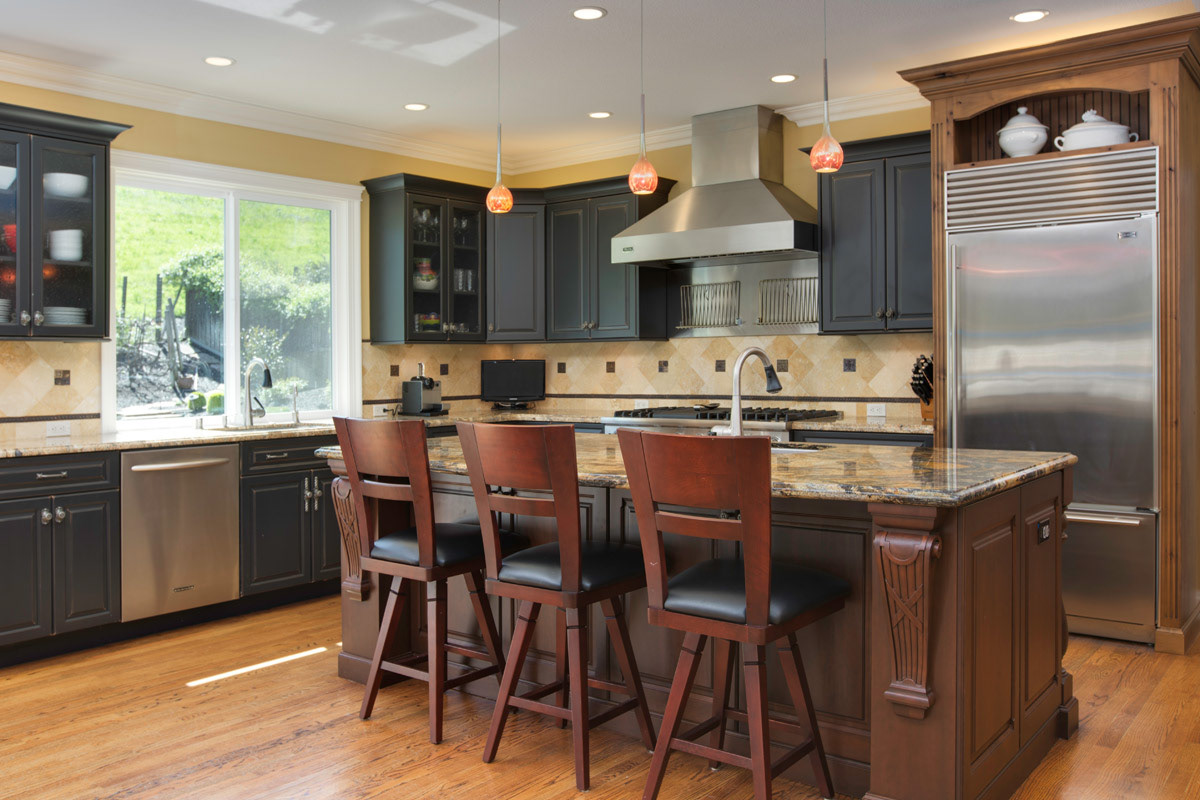 kitchen-with-warm-tones-black-cabinets-and-dark-wood-island-with-carved-corbels-and-solid-granite-counter