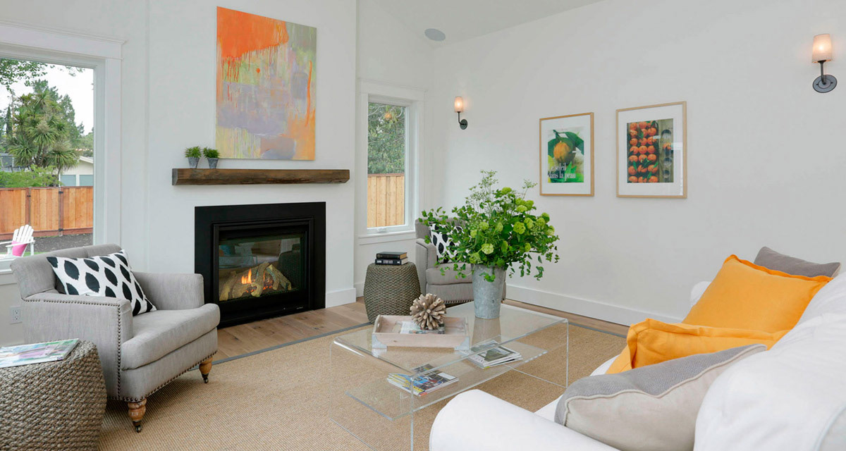 White-living-room-black-fireplace-wood-mantel-orange-accents