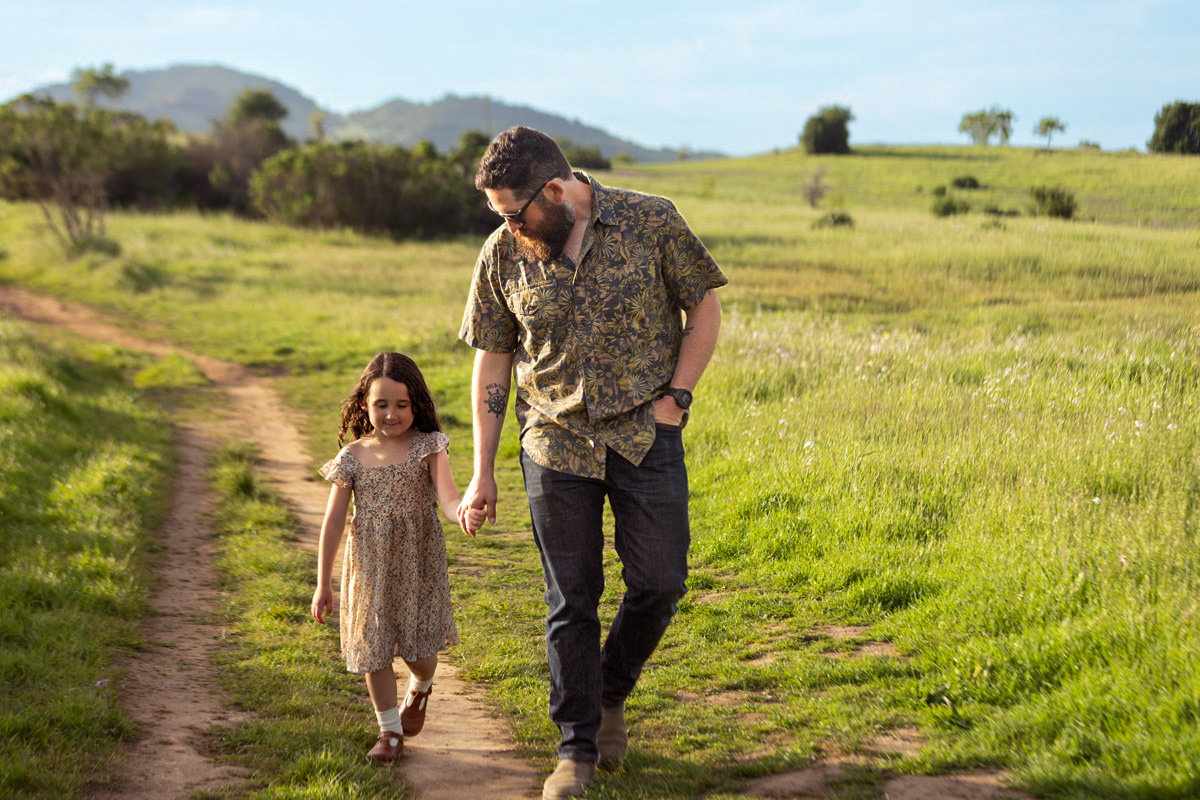 father-holds-young-daughters-hand-in-park