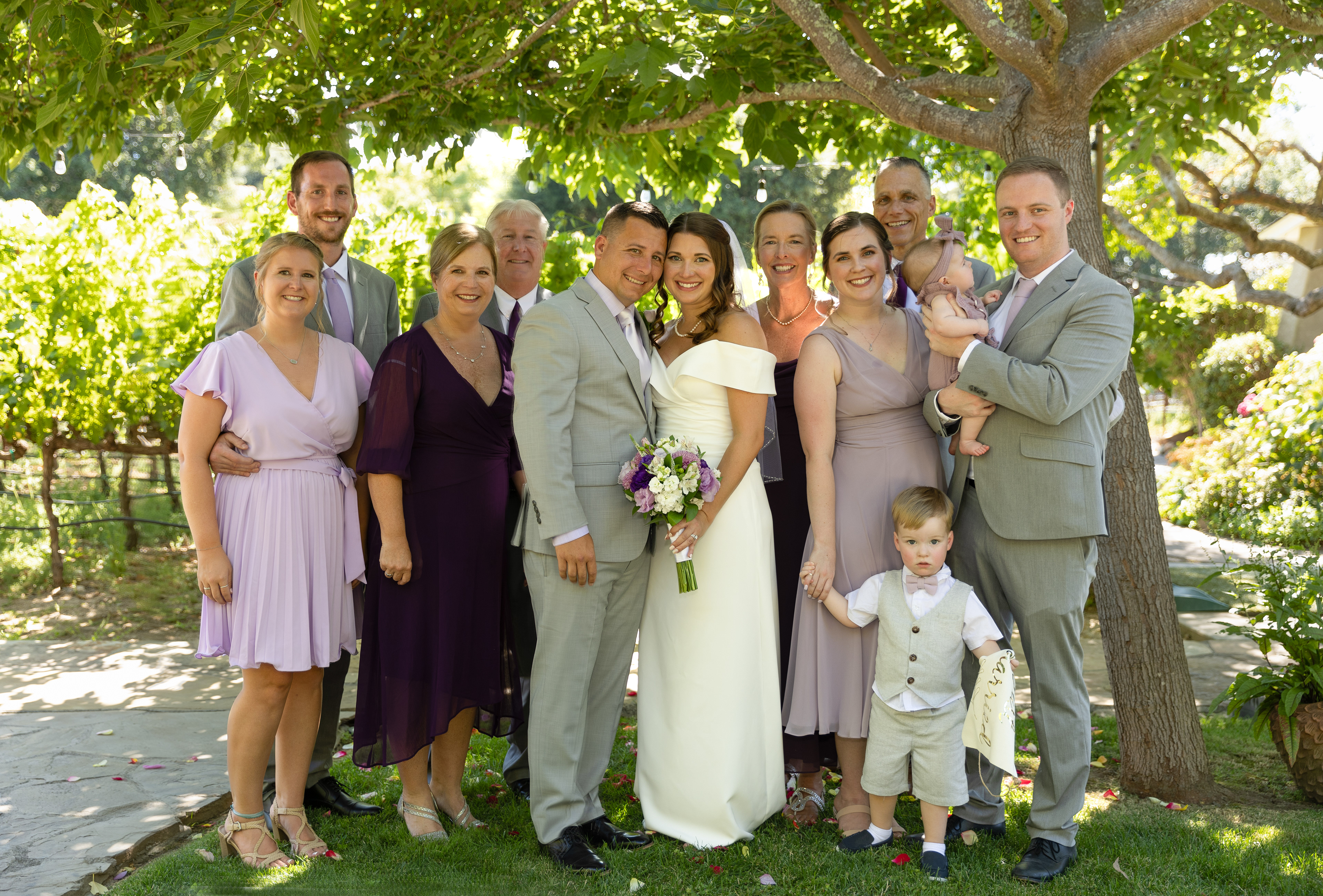 groom-and-bride-surrounded-by-family-in-front-of-grapevines