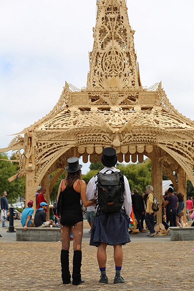 back of couple wearing top hats in front of wood pagoda