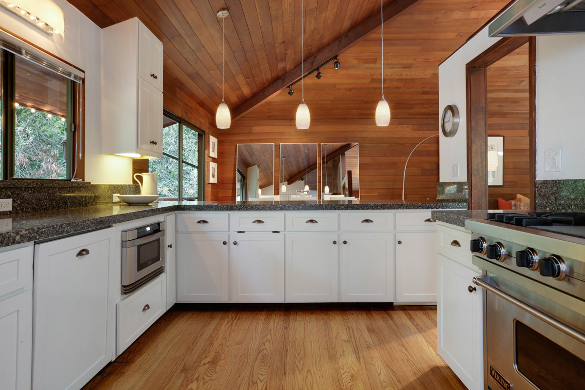 kitchen-with-pendant-lights-white-cabinets-and-wood-floors-walls-and-ceiling