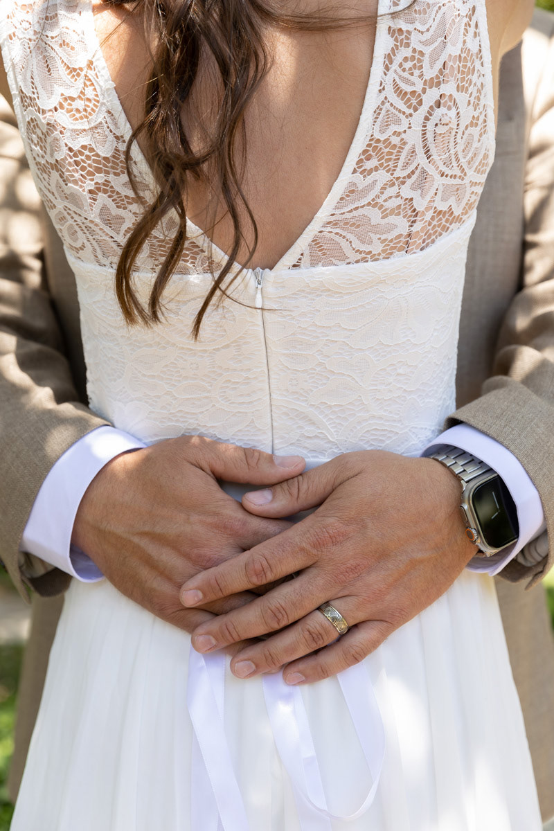 groom-embraces-the-bride's-waist-with-a-ringed-hand-overlapping-the-other-hand