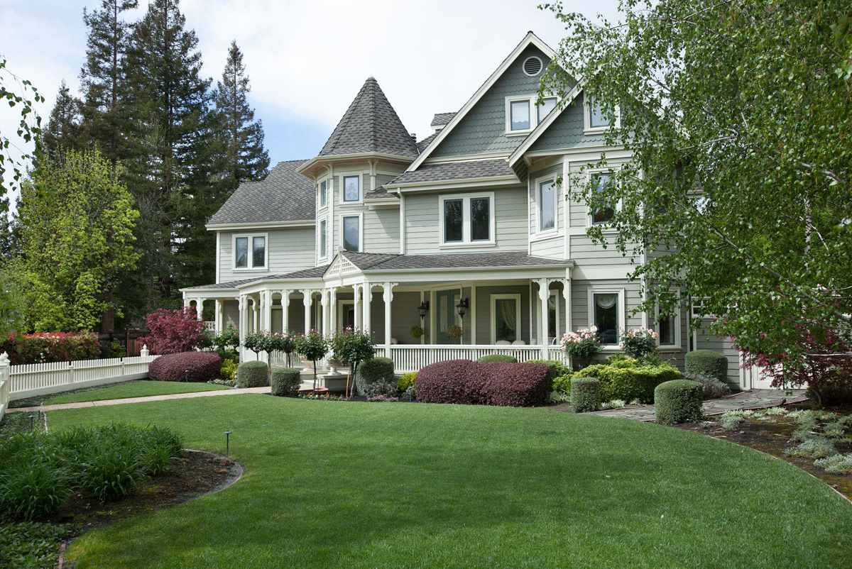 large-pale-green-victorian-house-with-wrap-around-porch-and-manicured-front-garden