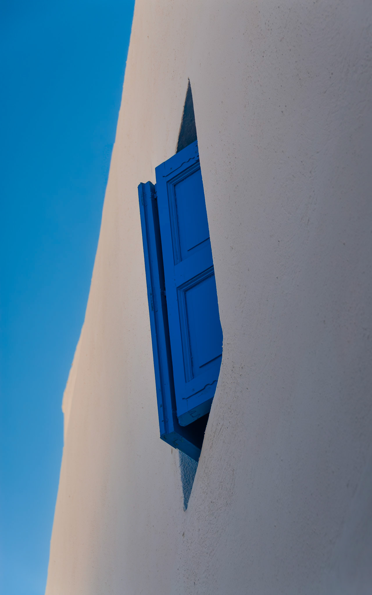 A vivid cobalt shutter pops against the whitewashed stucco of a Mykonos home.