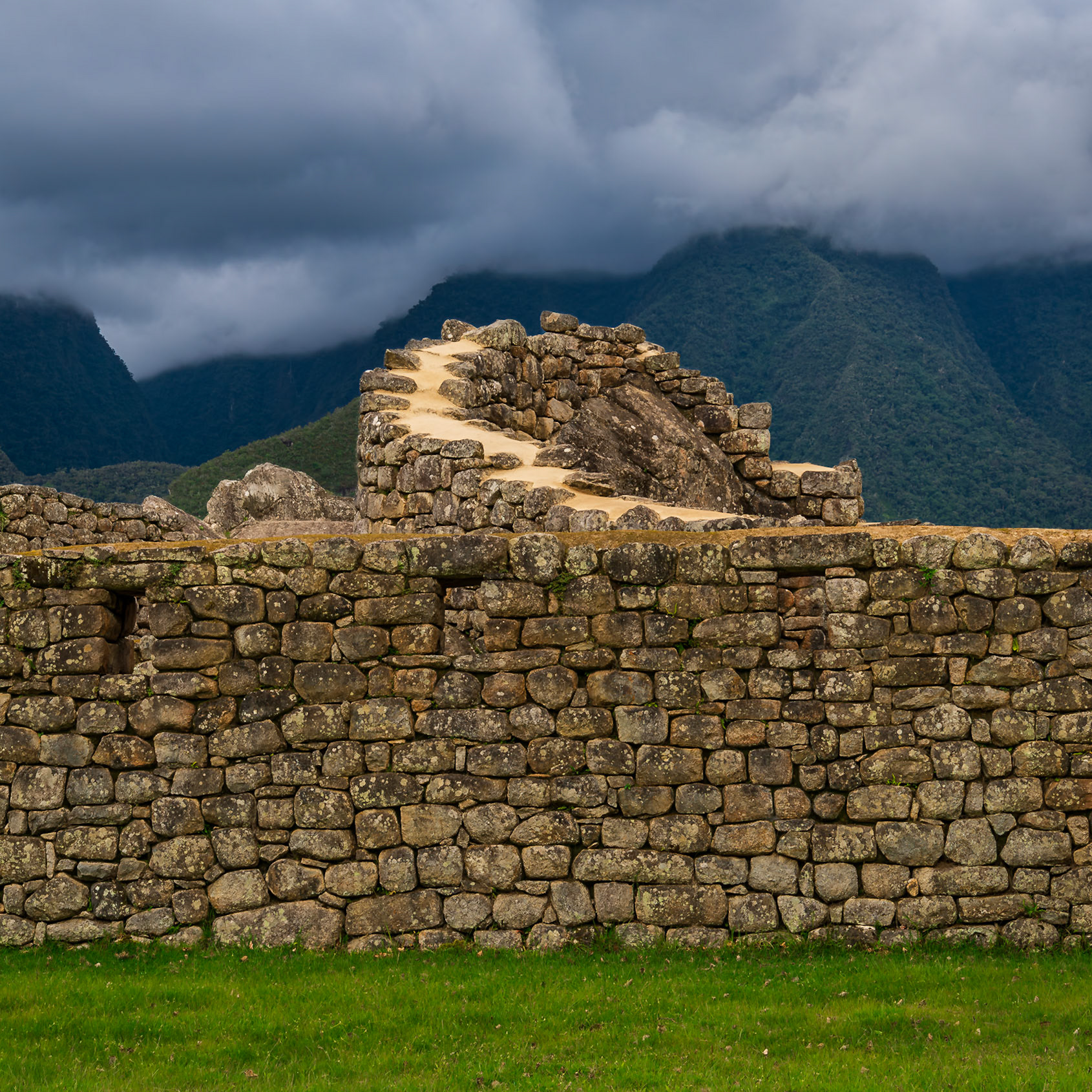 A spiraling stone path rises from fortress walls under a turbulent sky.