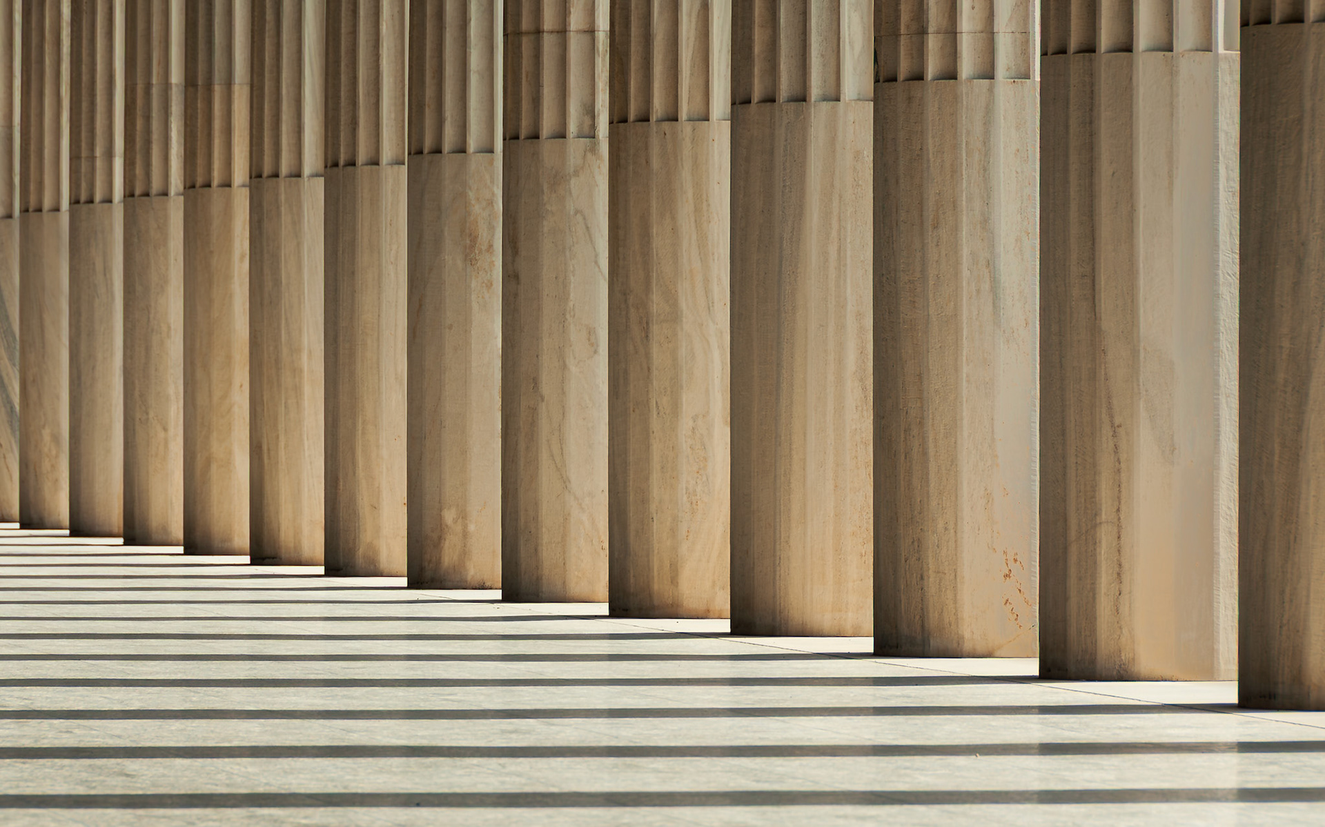 Columns of the Stoa of Attalos, Agora cast rhythmic shadows across polished stone in Athens.