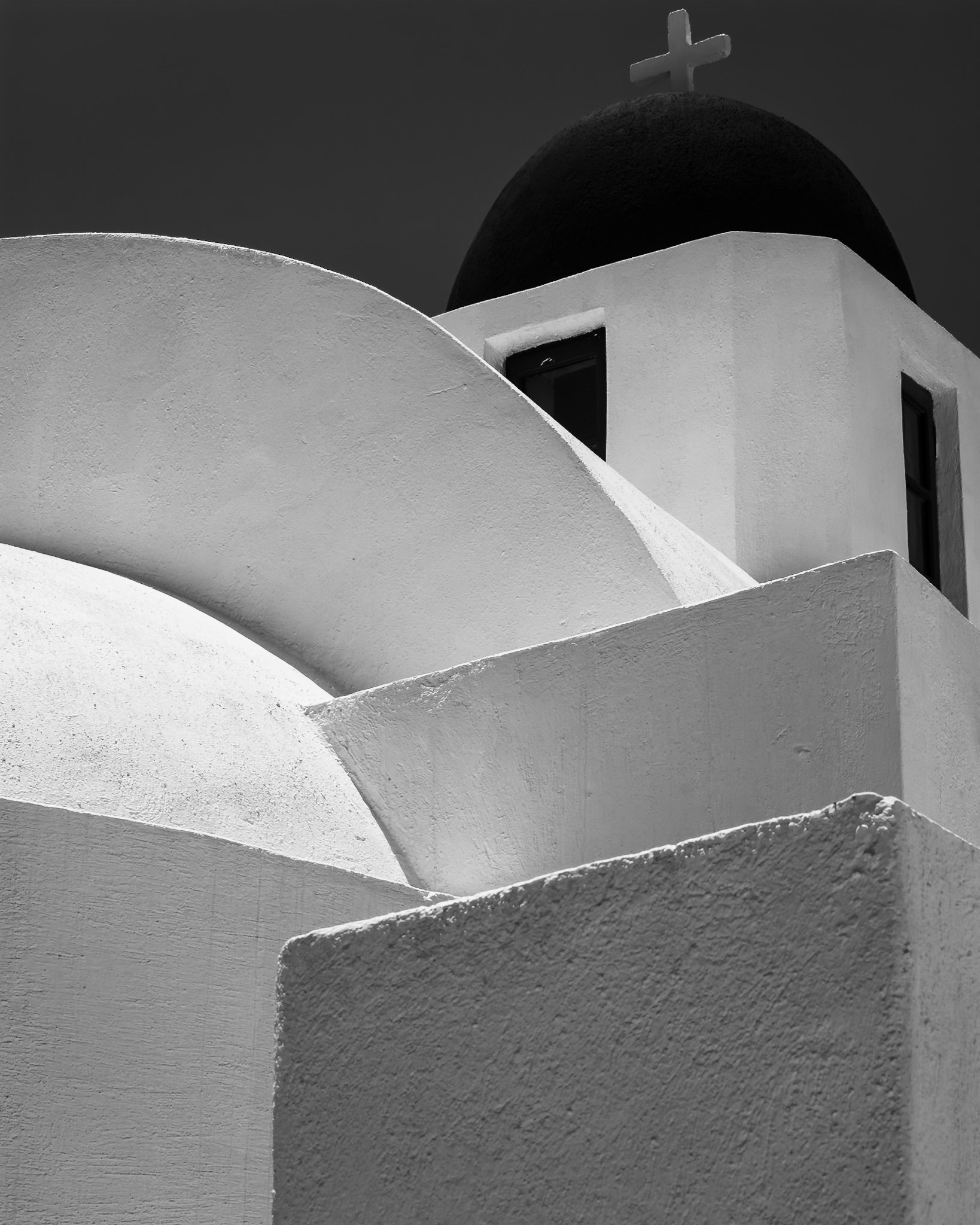 A study in form and contrast, this image emphasizes the bold geometry of a traditional Santorini church.