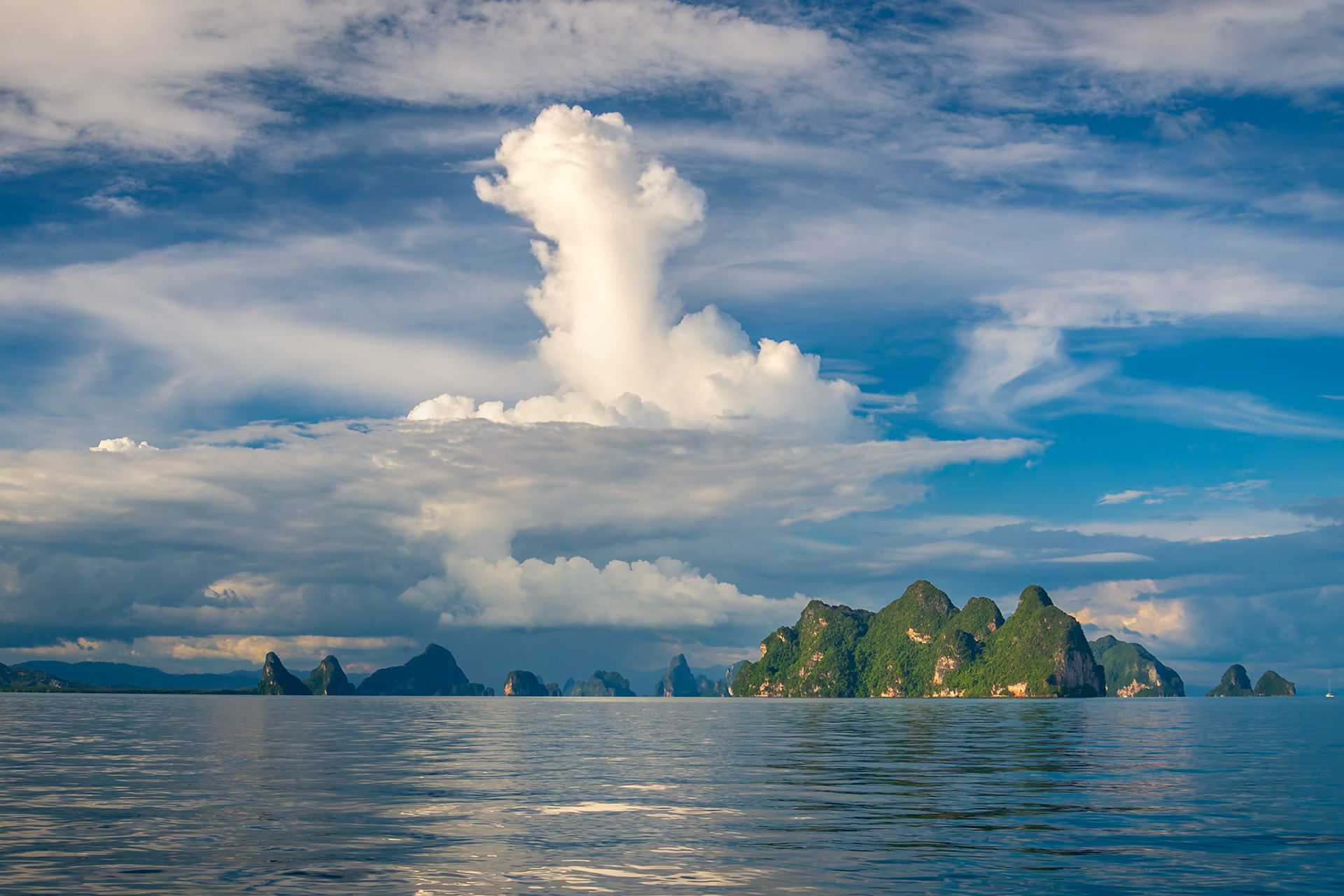 A vertical plume of white cloud forms above the jagged islands of the Andaman Sea.