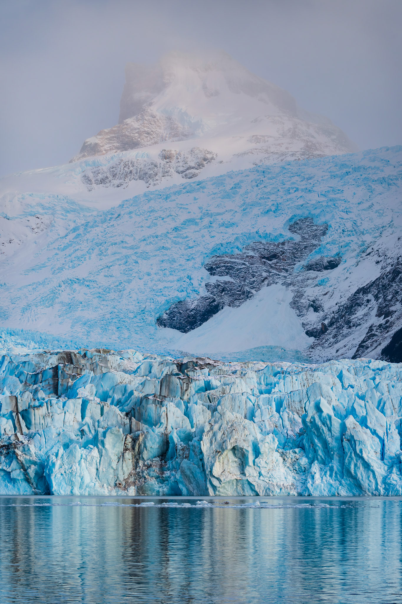 The sharp glacial face  buttressed by slow-moving radiant blue ice.
