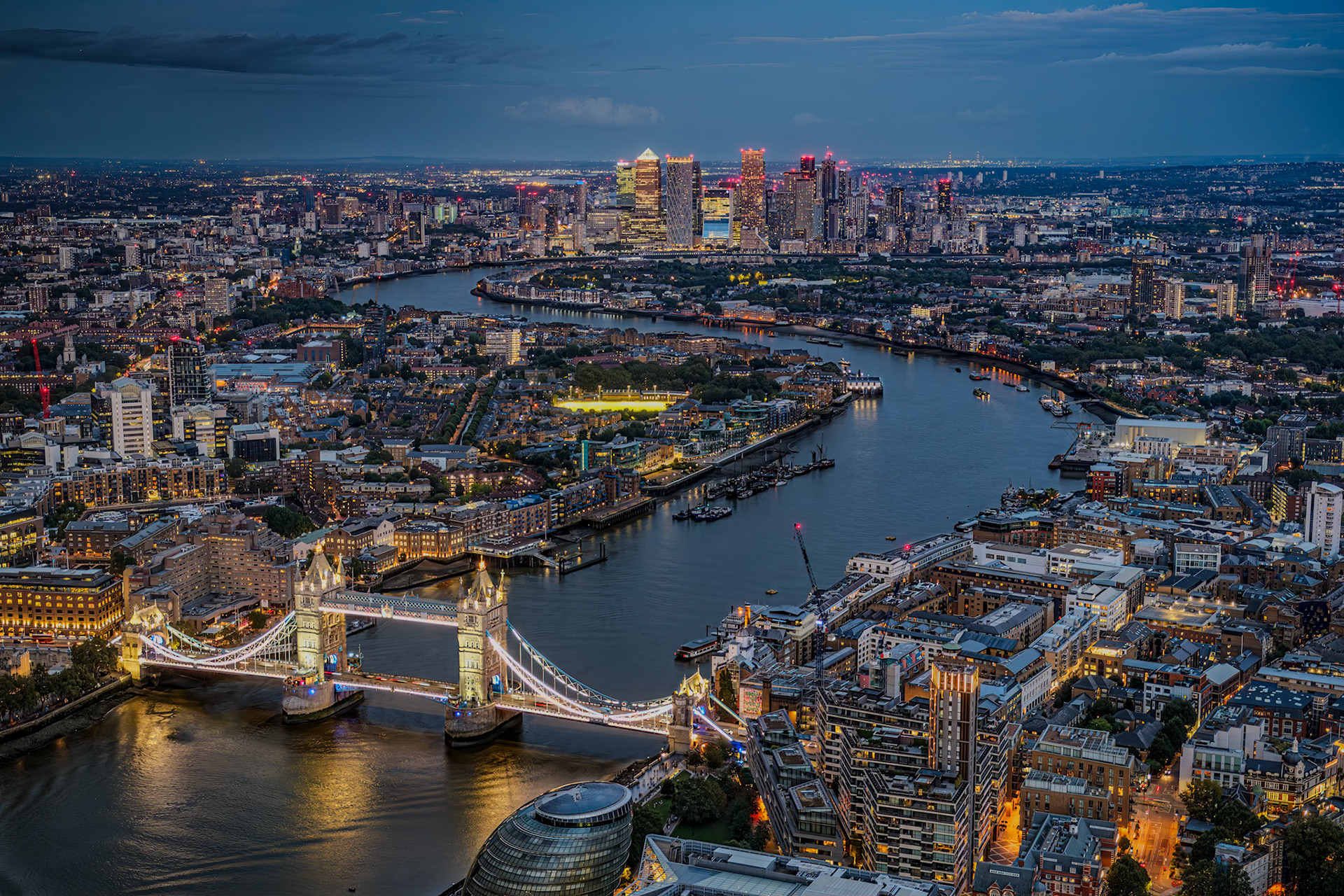 Fantastisk kvällsvy över Tower bridge och Themsen bort mot skyskraprona vid Canary Wharf