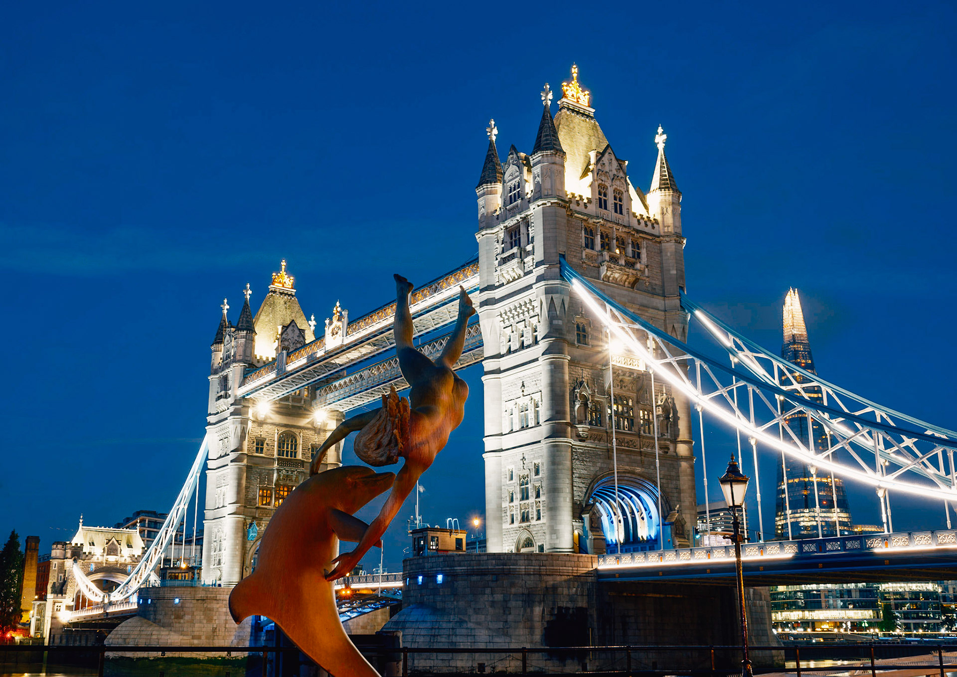Fontänen Flickan med delfinen med Tower Bridge i bakgrunden under blå timmen.