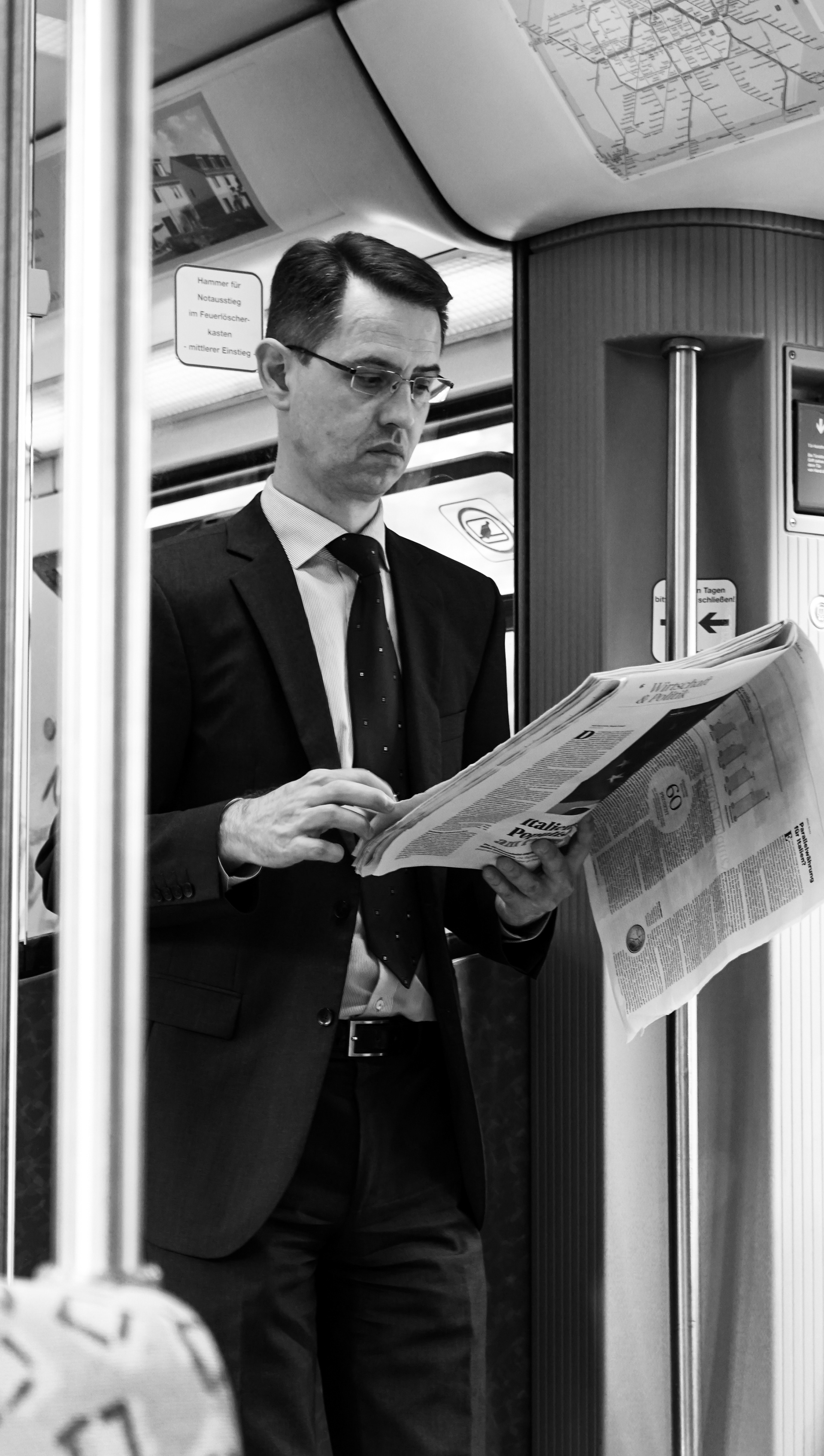black and white photography. Male is reading a newspaper in the underground London