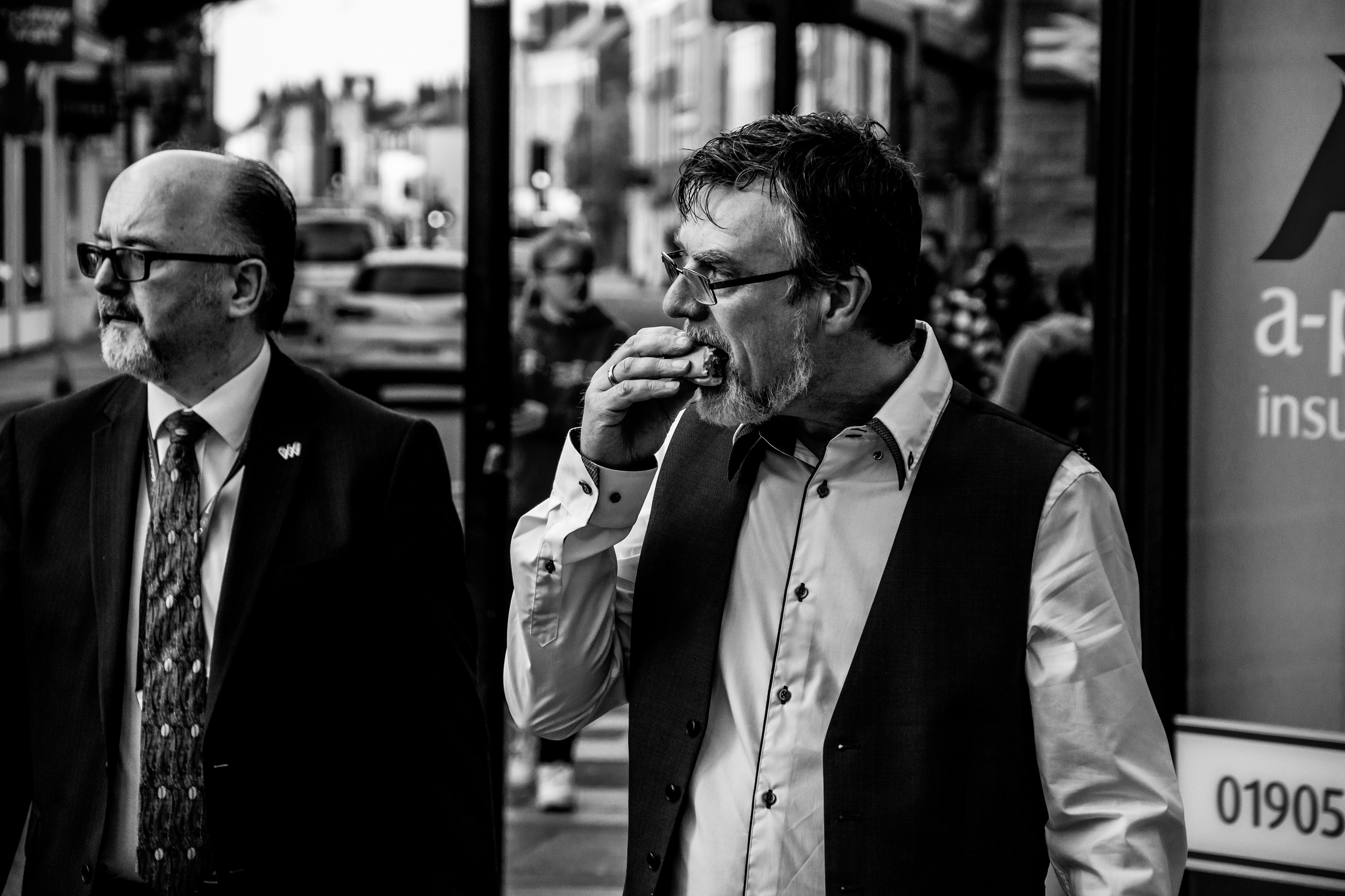Street photography black and white image. Man is eating while walking on the street of London. 