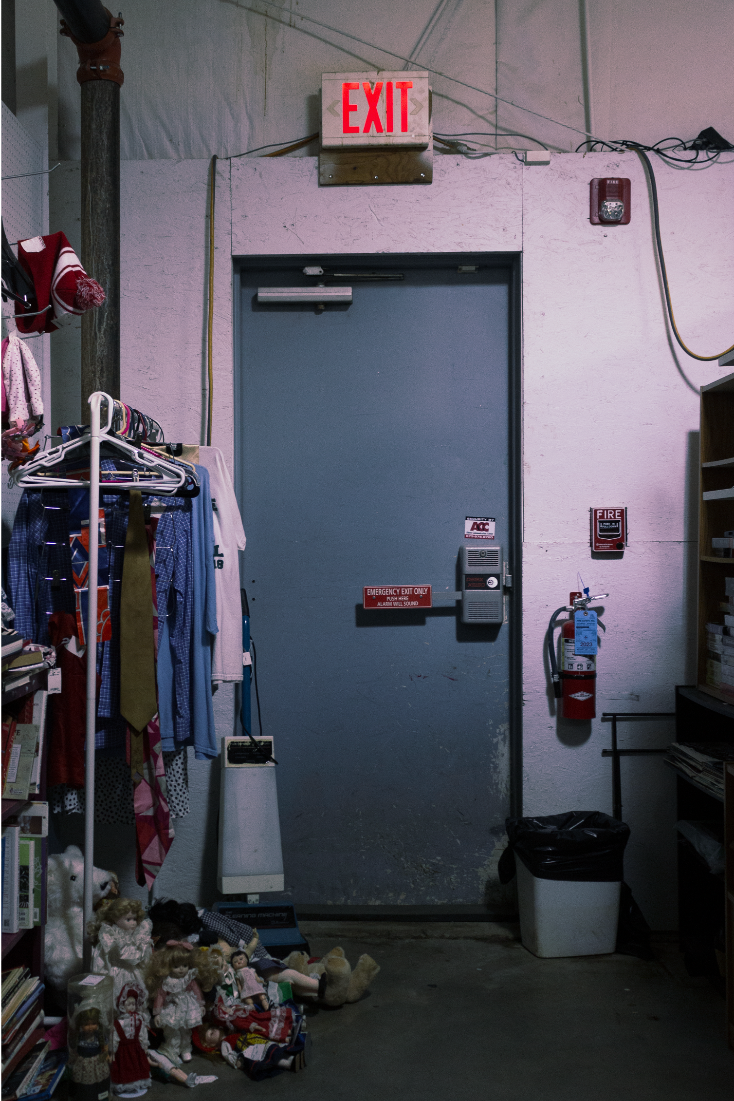 An exit door is framed by items such as clothing and dolls.