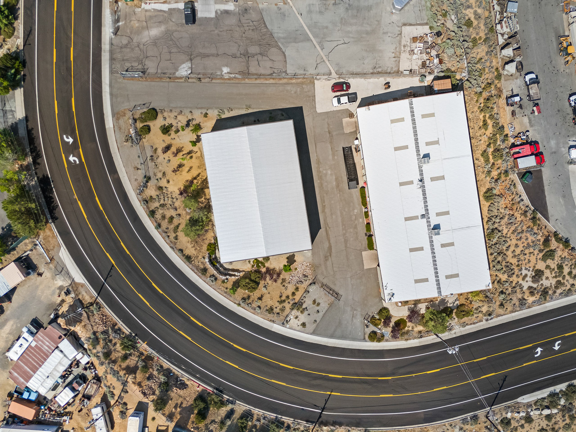 Top-down aerial of industrial buildings along a curved road