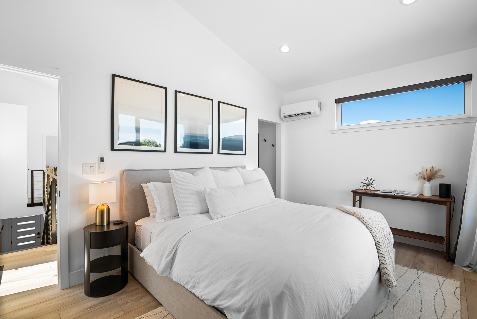 Interior real estate photography of modern master bedroom looking out towards the hallway and staircase landing in Temecula city home - Andrew Crippen Visuals