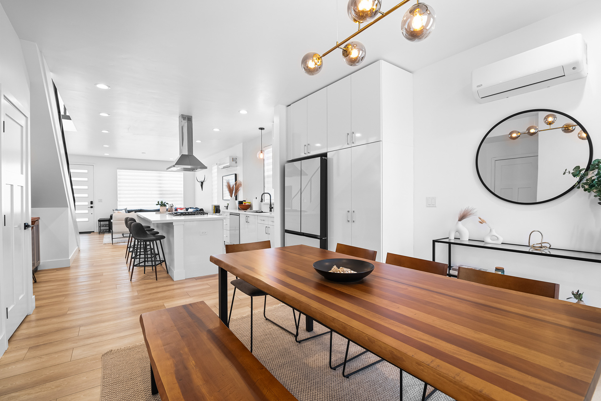 Interior real estate photography framing the ultra-modern kitchen from behind the custom wood dining table in Temecula city home - Andrew Crippen Visuals